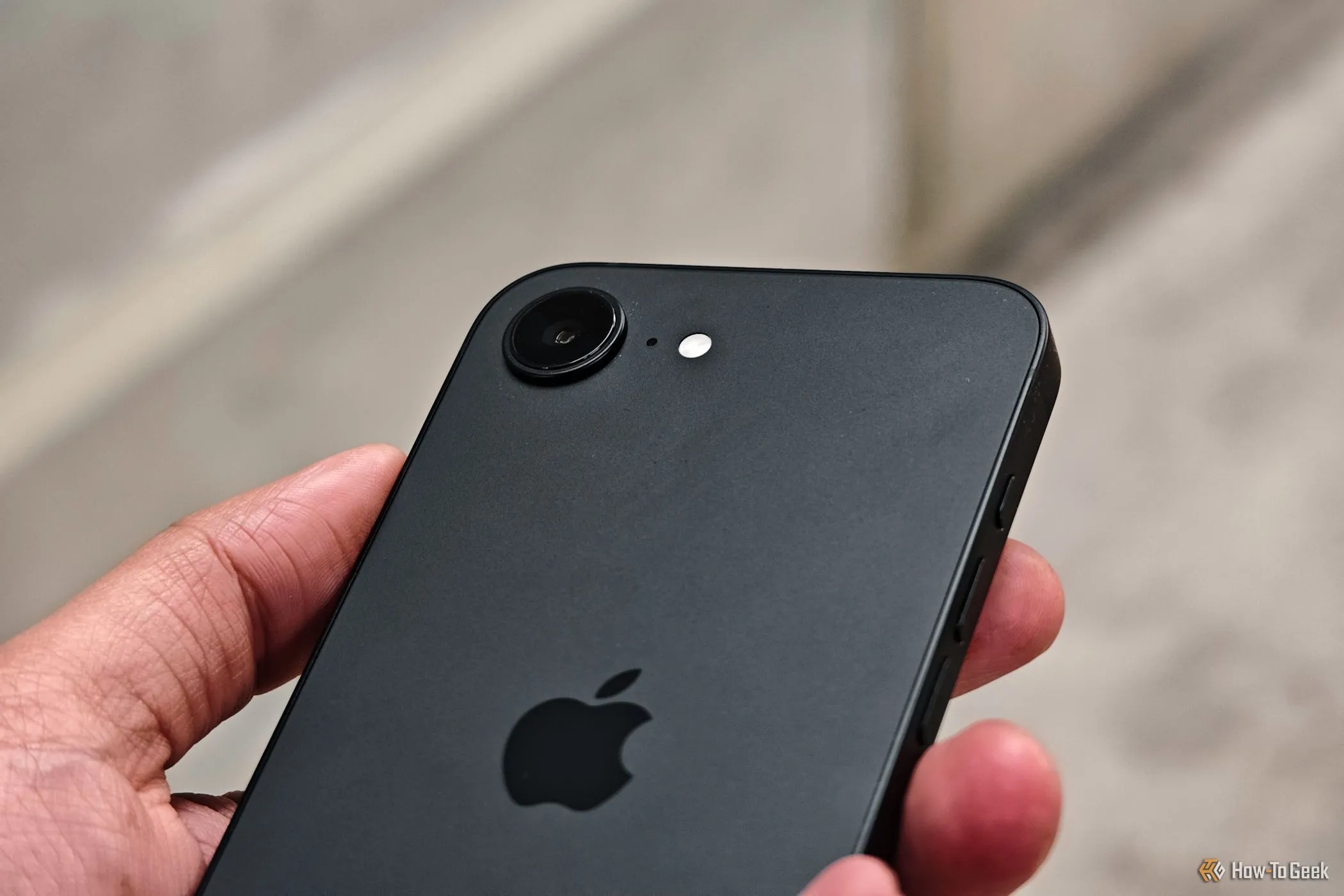 Ảnh cận cảnh cụm camera của iPhone 16e trên tay người dùng, thể hiện chi tiết thiết kế ống kính.