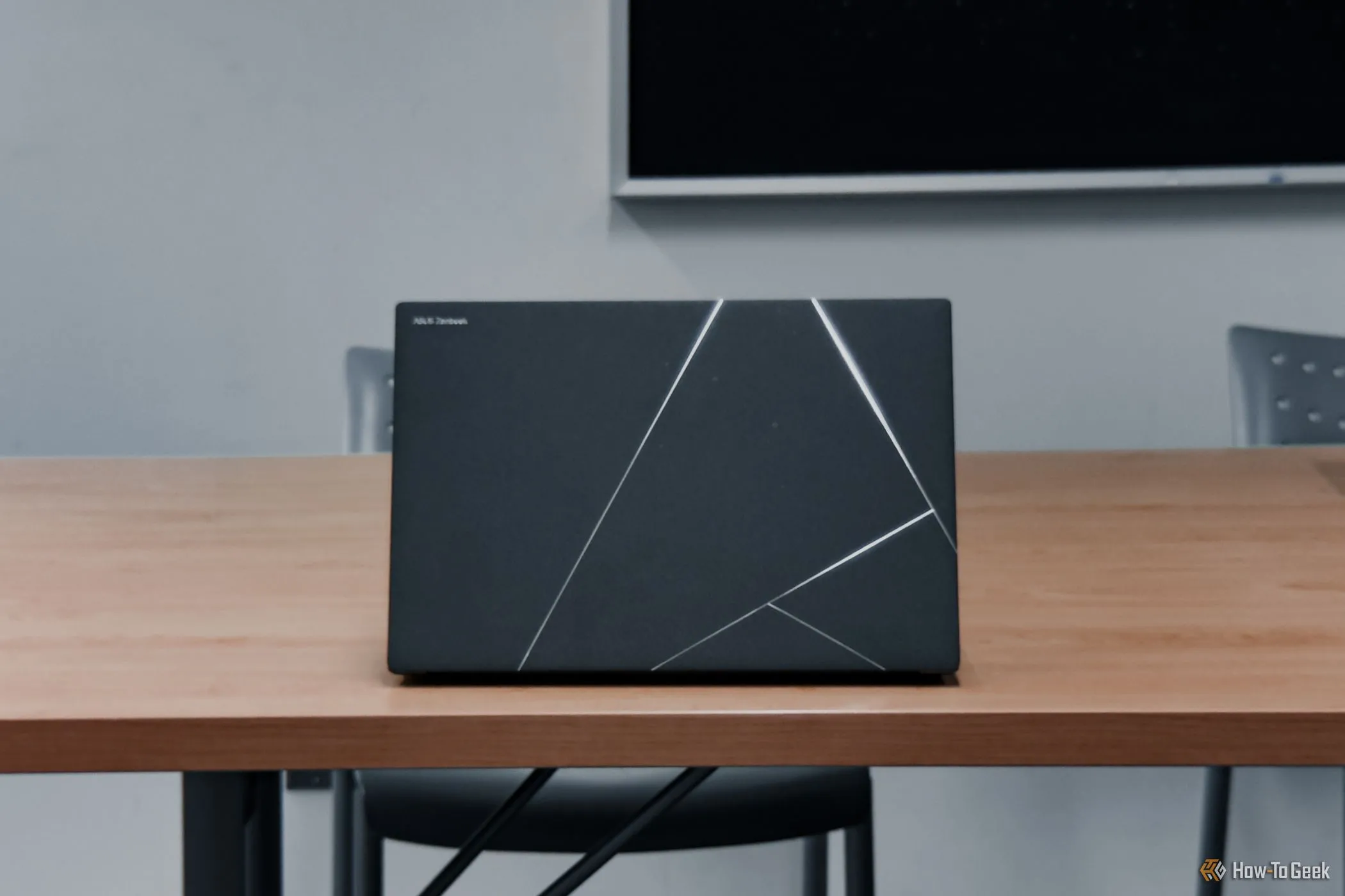 ASUS Zenbook S 14 back lid head-on, on wooden-table.