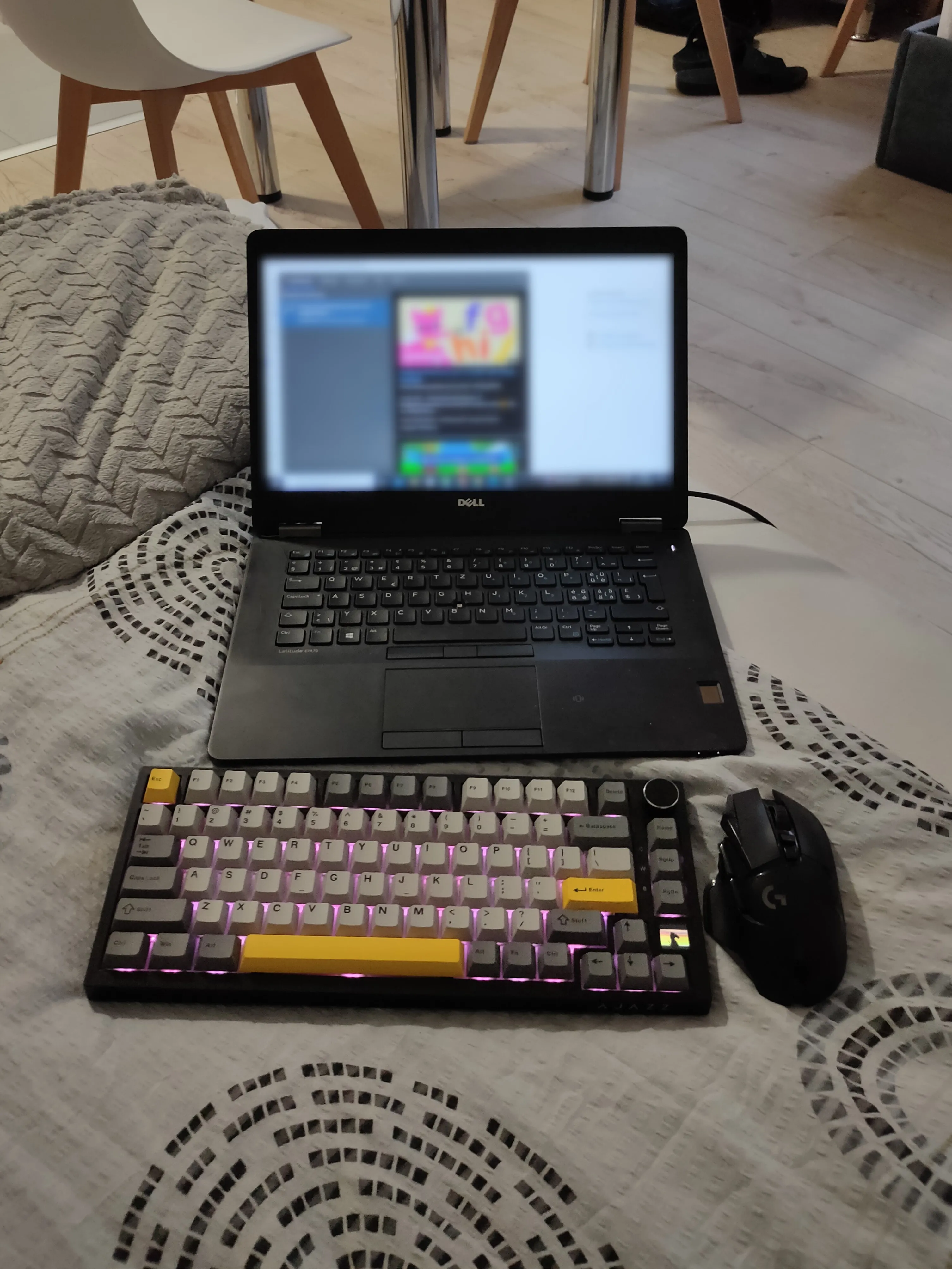 Bàn phím và chuột không dây đặt cạnh laptop trên giường, setup chơi game đơn giản và tiện lợi.