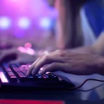 Bàn tay game thủ đang thao tác trên bàn phím máy tính xách tay, thể hiện khả năng chơi game trên laptop văn phòng.