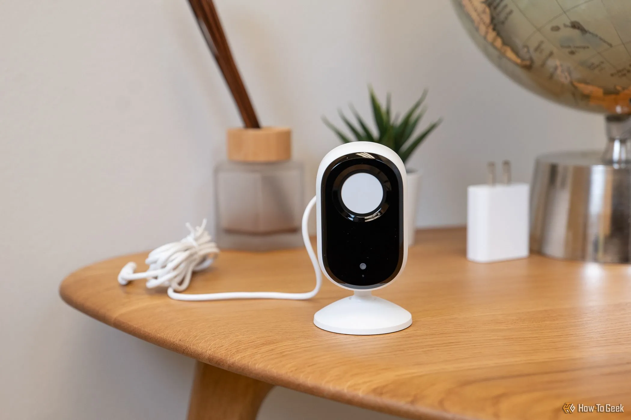Camera Arlo Essential Indoor Cam (2K) đặt trên bàn, màn che bảo mật đang đóng