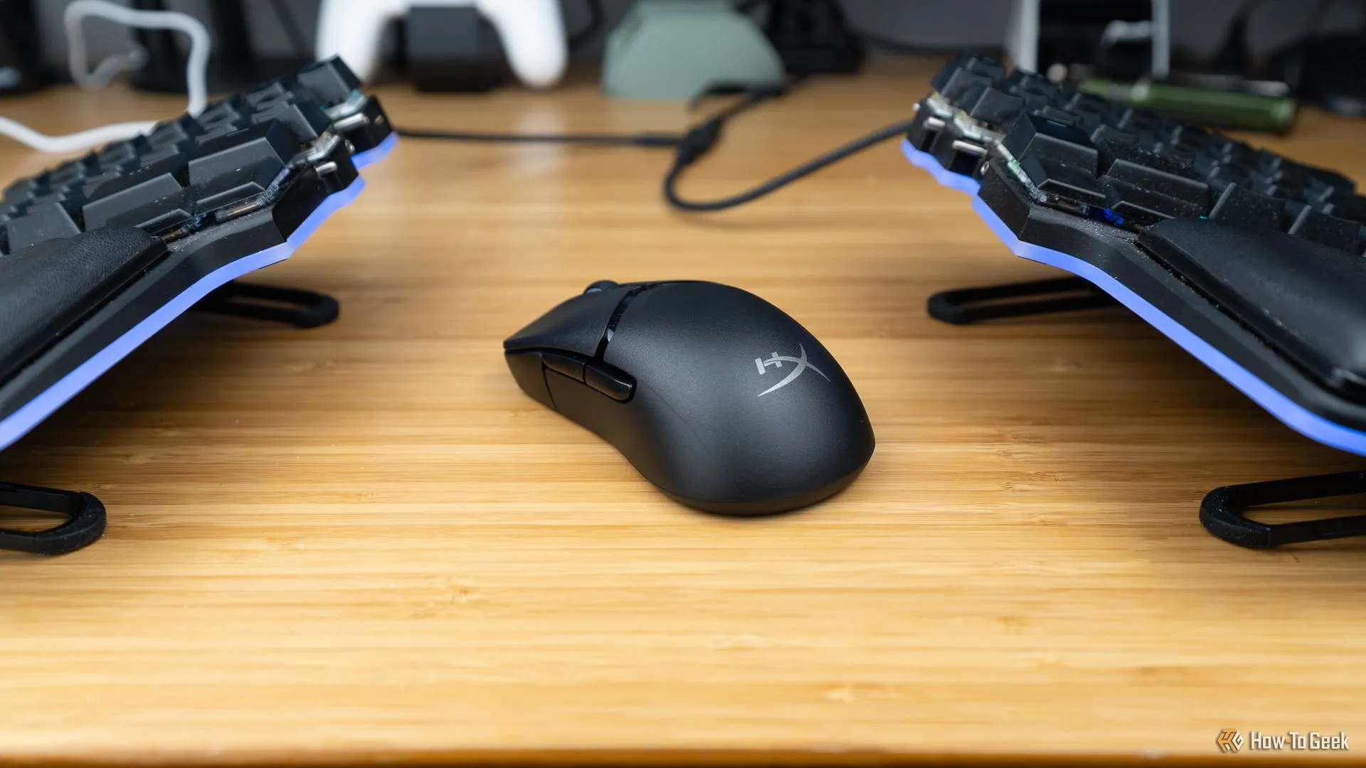 Chuột gaming không dây HyperX Pulsefire Saga Pro đặt giữa hai nửa bàn phím cơ, tạo không gian setup gaming
