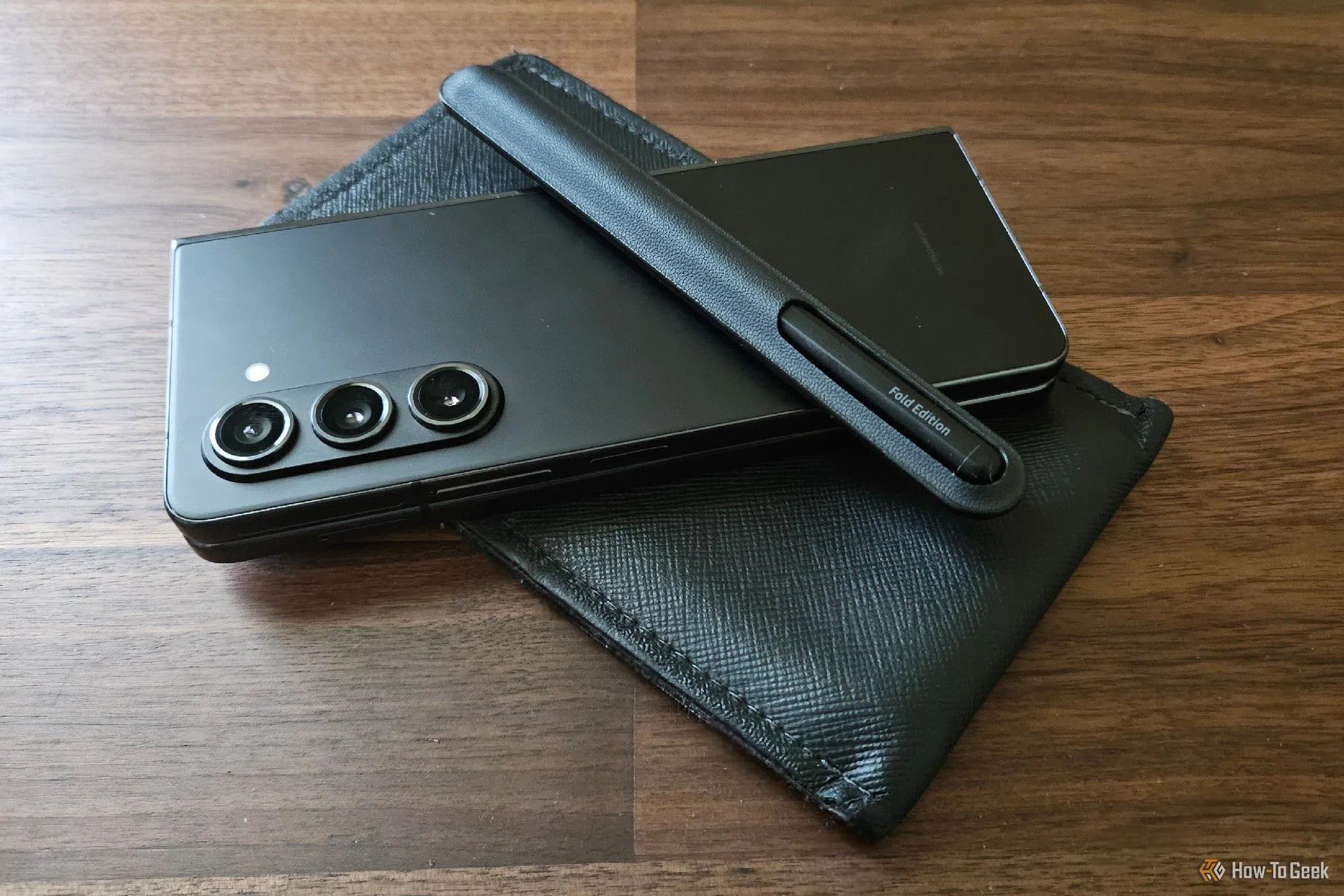 Điện thoại Samsung Galaxy Z Fold 5 đặt trong bao da cùng bút S Pen Fold Edition lớn, cho thấy cách người dùng mang theo phụ kiện.