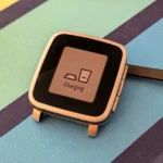 Đồng hồ thông minh Pebble Time Steel đang được sạc, gợi nhớ đến khả năng tương thích của ứng dụng Pebble mới với các mẫu cũ.