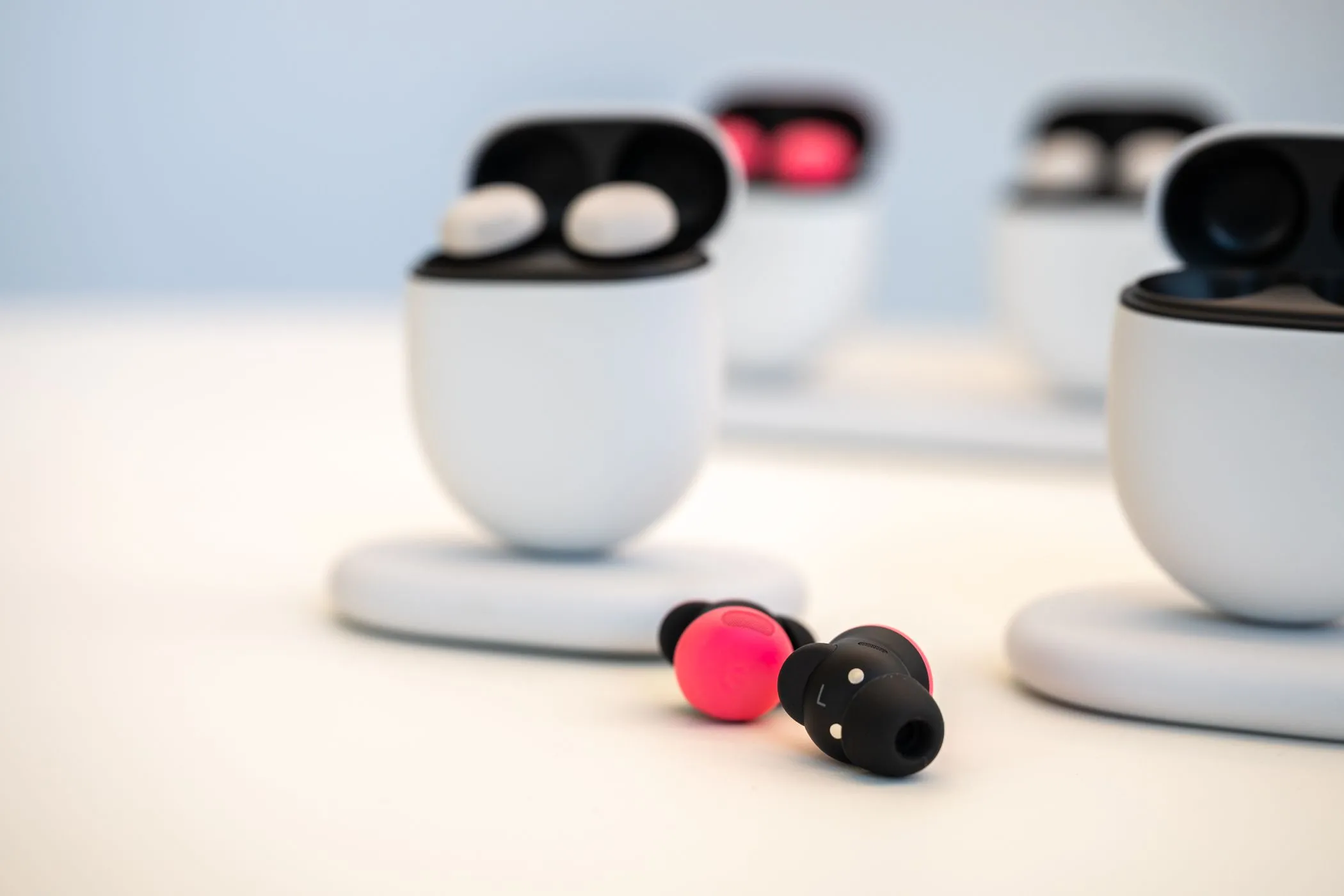 Google Pixel Buds Pro 2 màu hồng Peony đặt cạnh hộp sạc trên mặt bàn