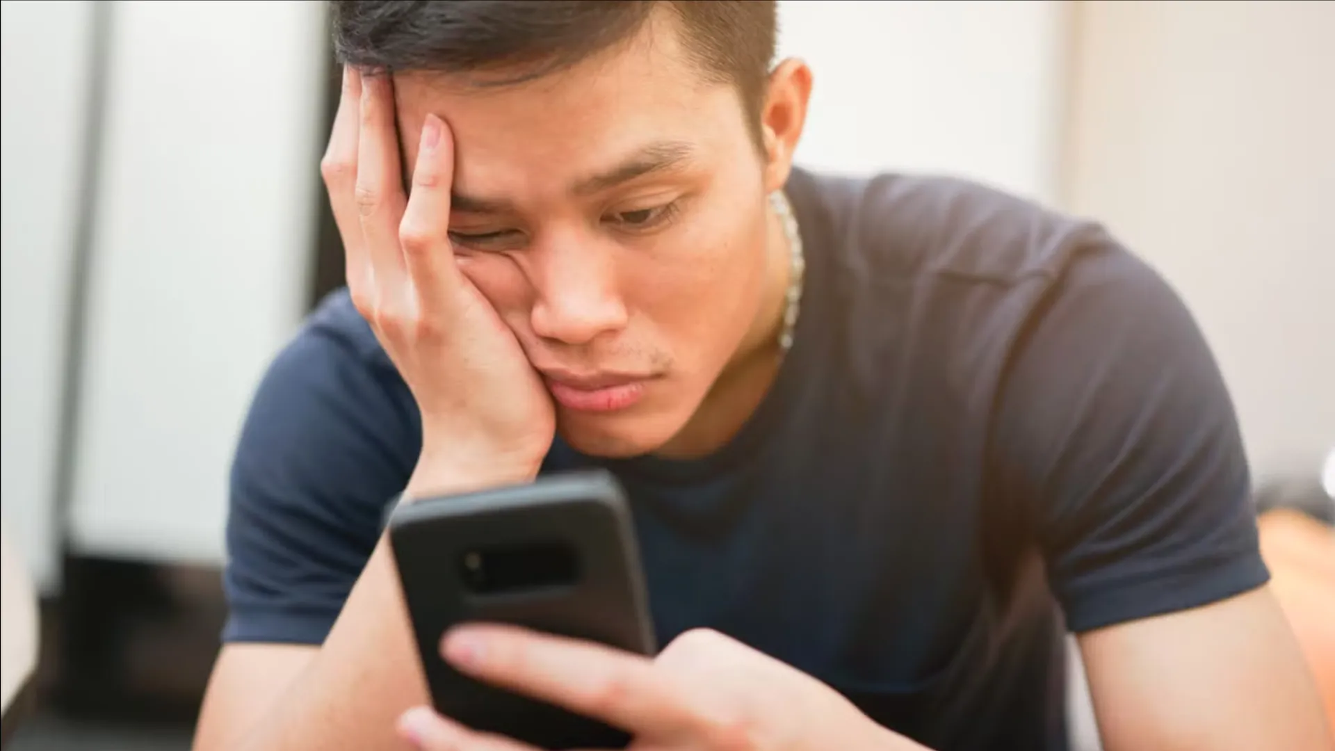 Hình ảnh một người dùng đang lướt điện thoại với vẻ mặt nhàm chán, minh họa hành vi lãng phí thời gian.