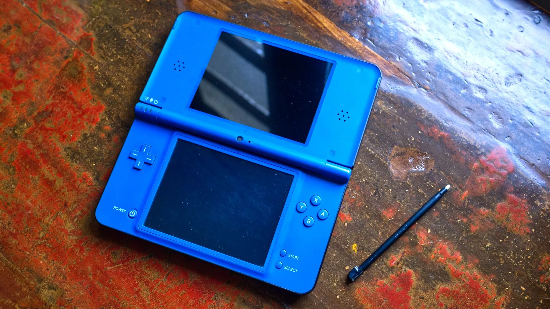 Máy chơi game Nintendo DSi XL màu xanh đang mở, biểu tượng của kỷ nguyên handheld gọn nhẹ
