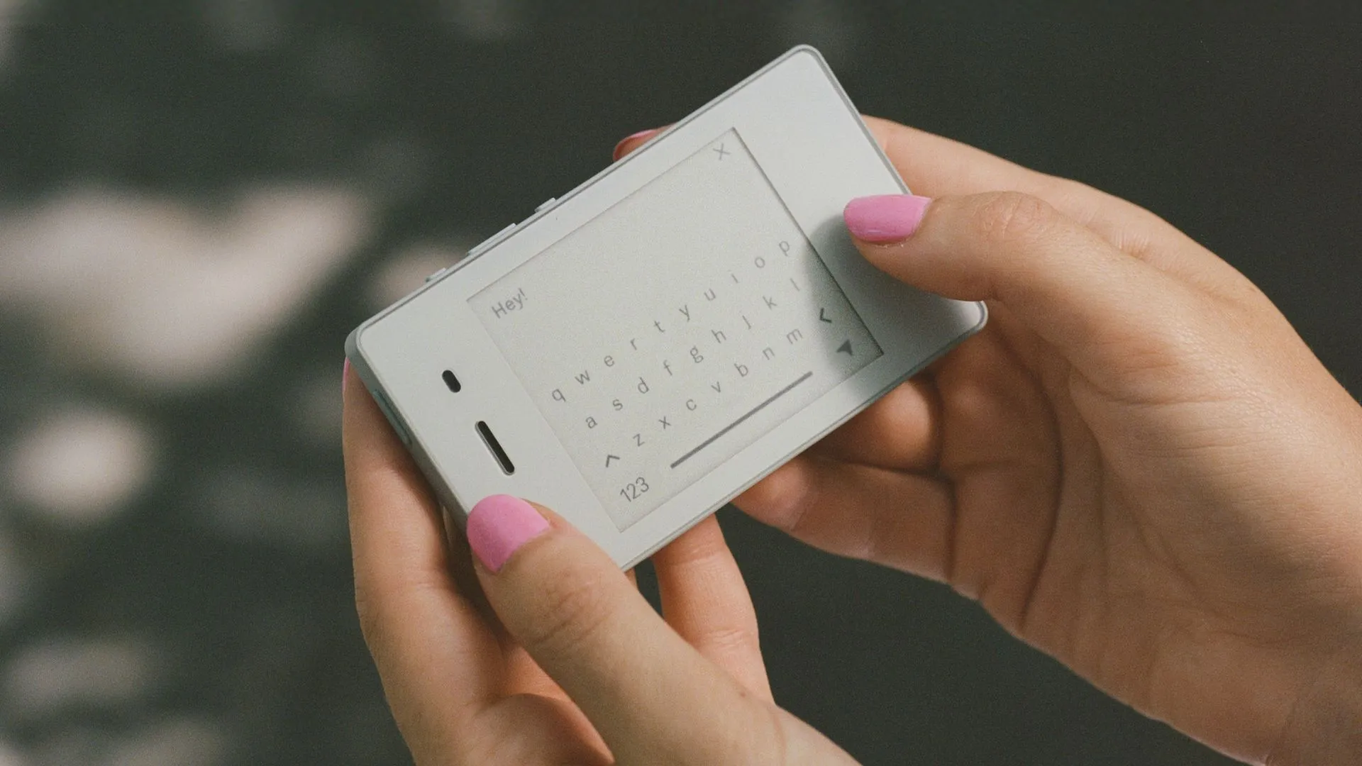 Một người đang cầm chiếc điện thoại Light Phone 2 màu đen với màn hình e-ink hiển thị giờ và thông báo.