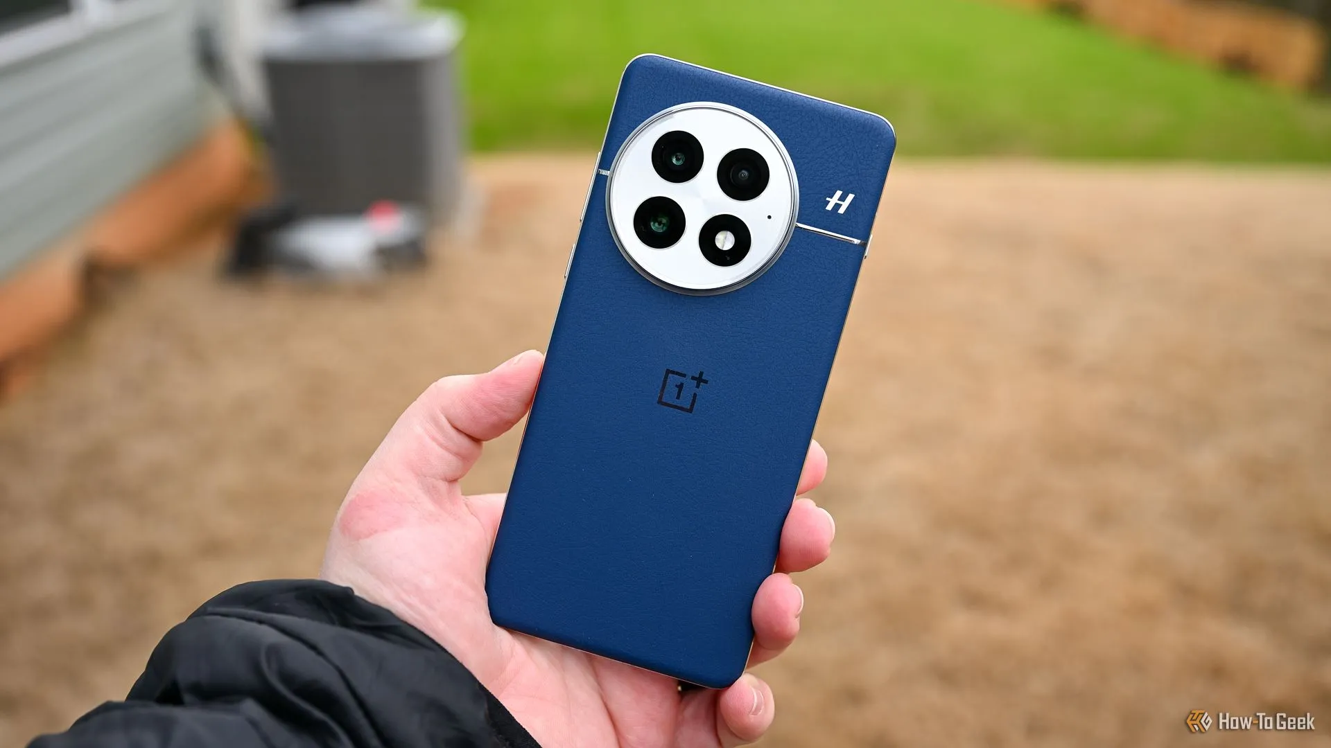 Một người đang cầm chiếc điện thoại OnePlus 13 màu xanh dương, làm nổi bật mặt lưng và cụm camera, đại diện cho smartphone sử dụng pin silicon-carbon dung lượng lớn.