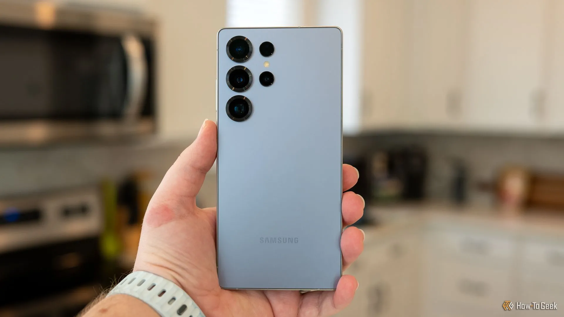 Người dùng đang cầm Galaxy S25 Ultra, cho thấy mặt lưng với cụm camera sau, bao gồm ống kính telephoto.