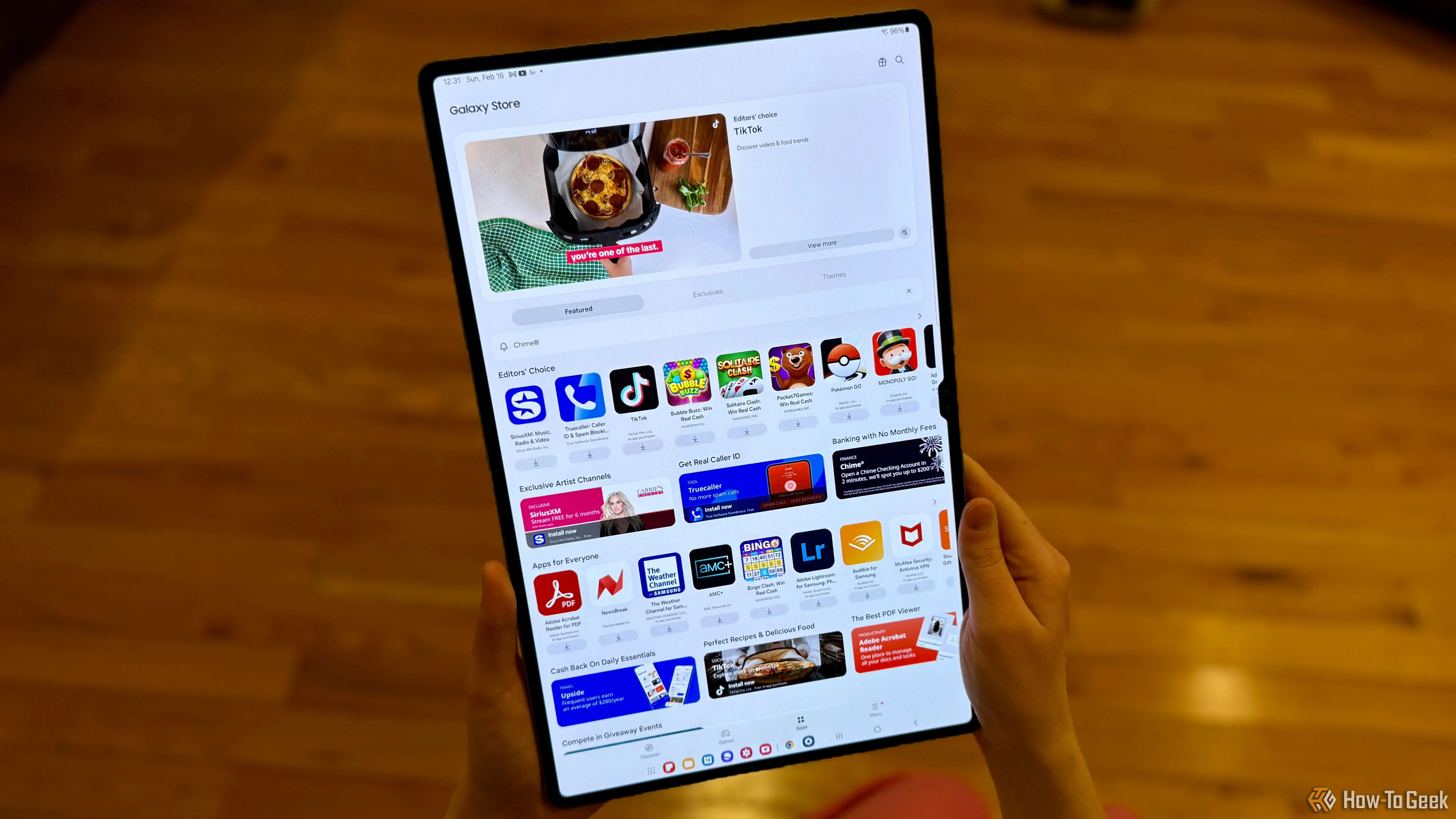 Người dùng đang cầm máy tính bảng Samsung Galaxy Tab S10 Ultra hiển thị cửa hàng Galaxy Store, thể hiện kích thước lớn và tỷ lệ màn hình rộng của tablet.