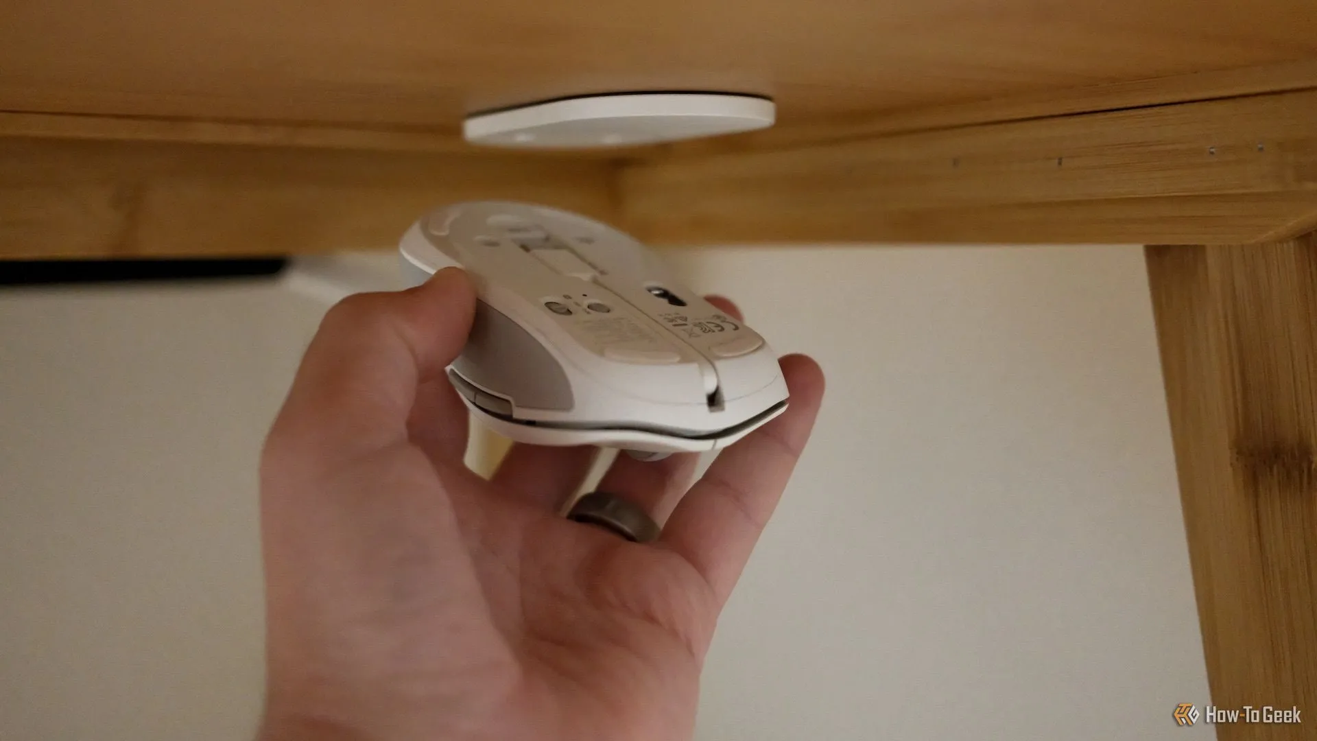 Người dùng đang gắn chuột ESR MagMouse vào đế từ tính đi kèm, minh họa tính năng kết nối từ.