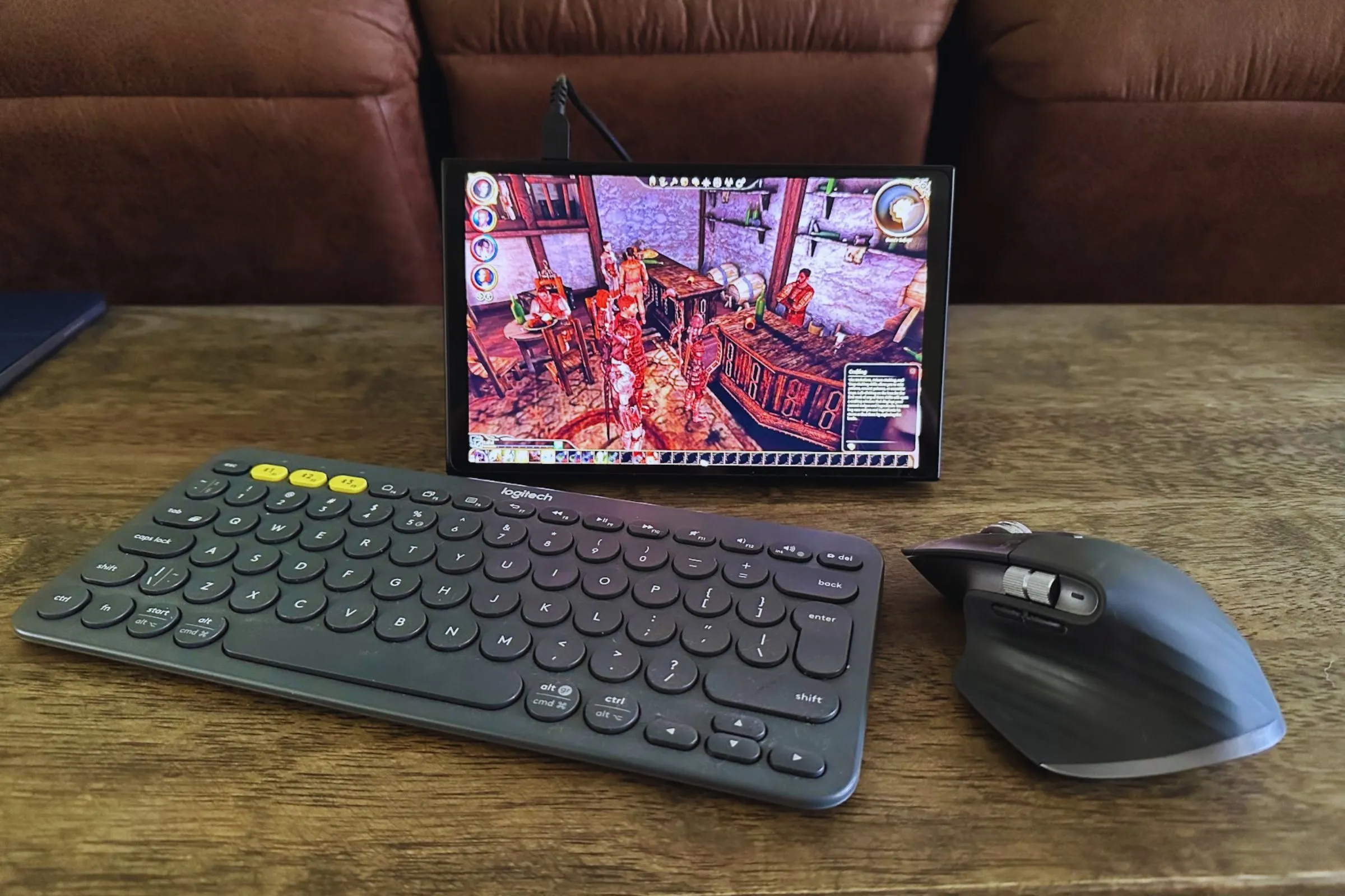 Bàn phím Logitech K380, chuột MX Master 3S và thiết bị chơi game cầm tay Lenovo Legion Go đặt trên bàn gỗ, minh họa sự linh hoạt khi sử dụng bàn phím chuột cho gaming.