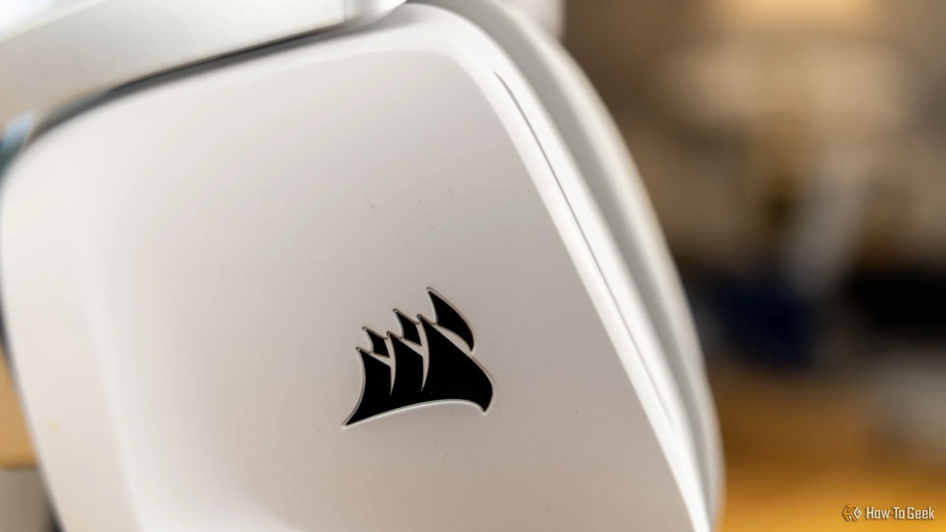 Cận cảnh logo CORSAIR trên chụp tai màu trắng của tai nghe Void Wireless V2, biểu tượng của thời lượng pin dài