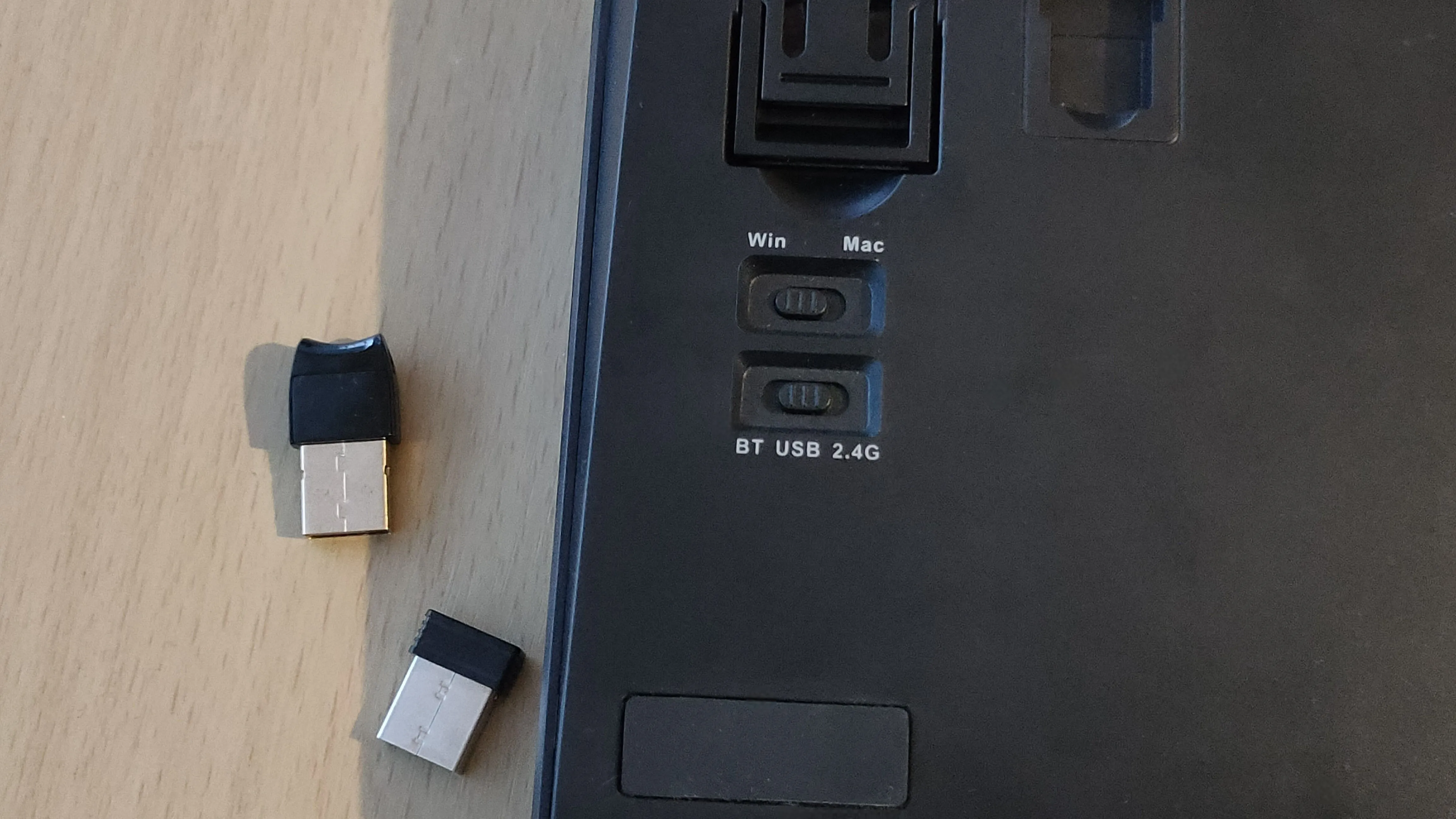Công tắc chế độ kết nối (Bluetooth/USB/2.4G) ở mặt sau bàn phím và các dongle USB đi kèm.