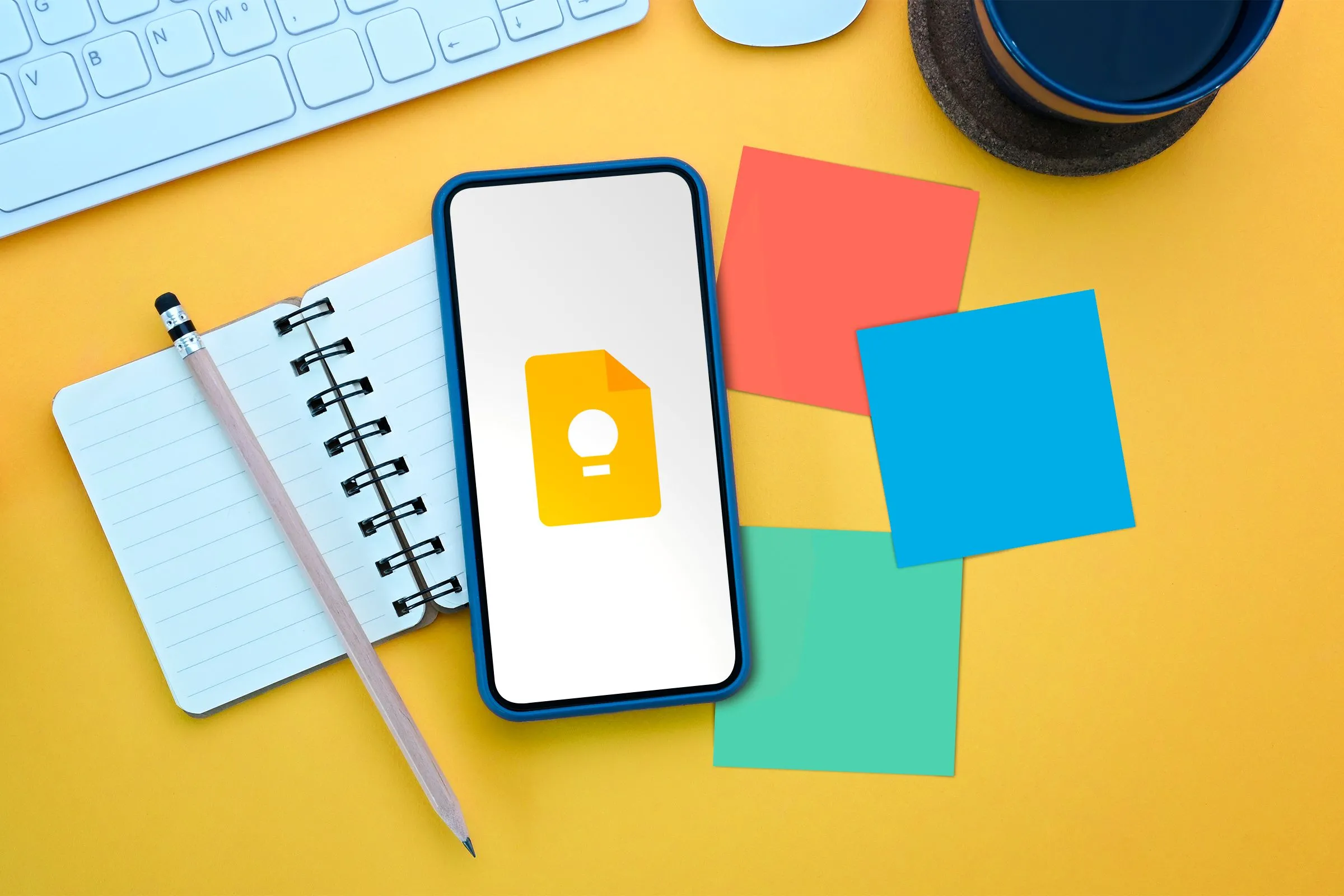 Điện thoại hiển thị ứng dụng Google Keep Notes đặt cạnh sổ tay và giấy ghi chú, biểu tượng cho việc quản lý công việc hiệu quả