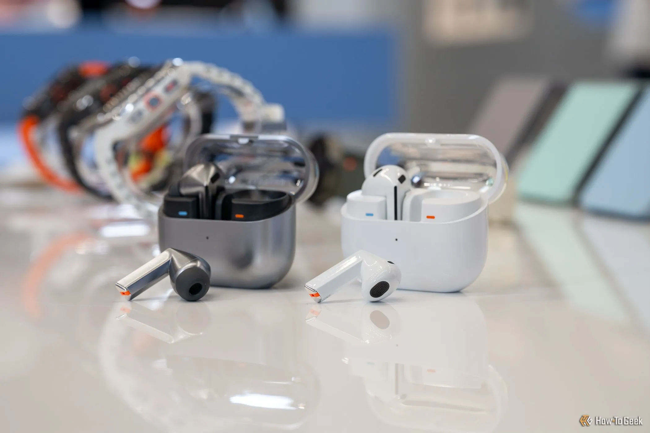 Hai cặp tai nghe Samsung Galaxy Buds 3 Pro và Galaxy Buds 3 đặt trên bàn, một chiếc đặt nghiêng và một chiếc đặt thẳng