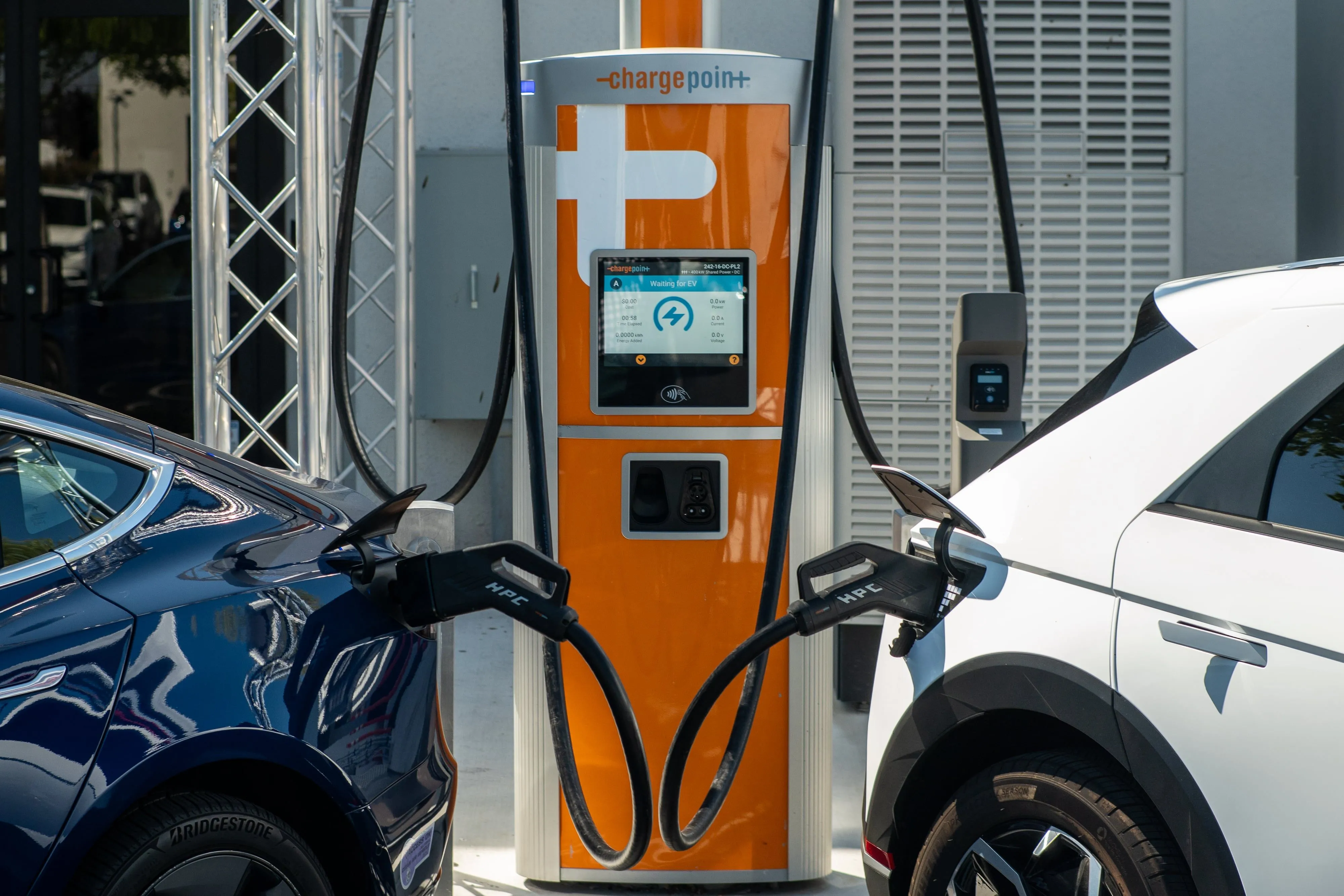 Hai xe ô tô điện đang sạc tại trạm sạc ChargePoint công cộng, minh họa sự phụ thuộc vào ứng dụng.