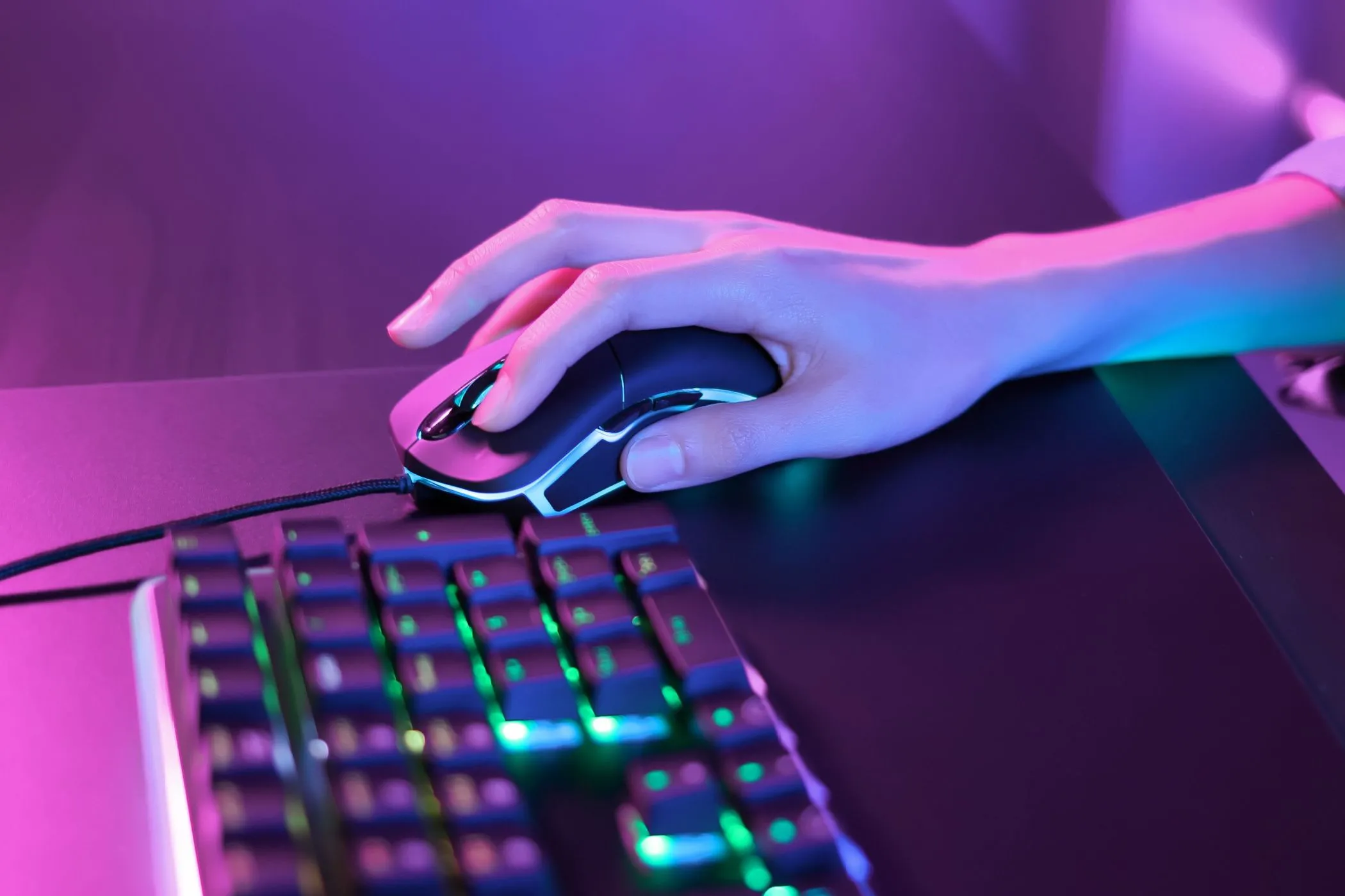Hình ảnh cận cảnh người chơi sử dụng chuột gaming và bàn phím RGB, thể hiện kỹ năng thao tác phức tạp của PC gaming.
