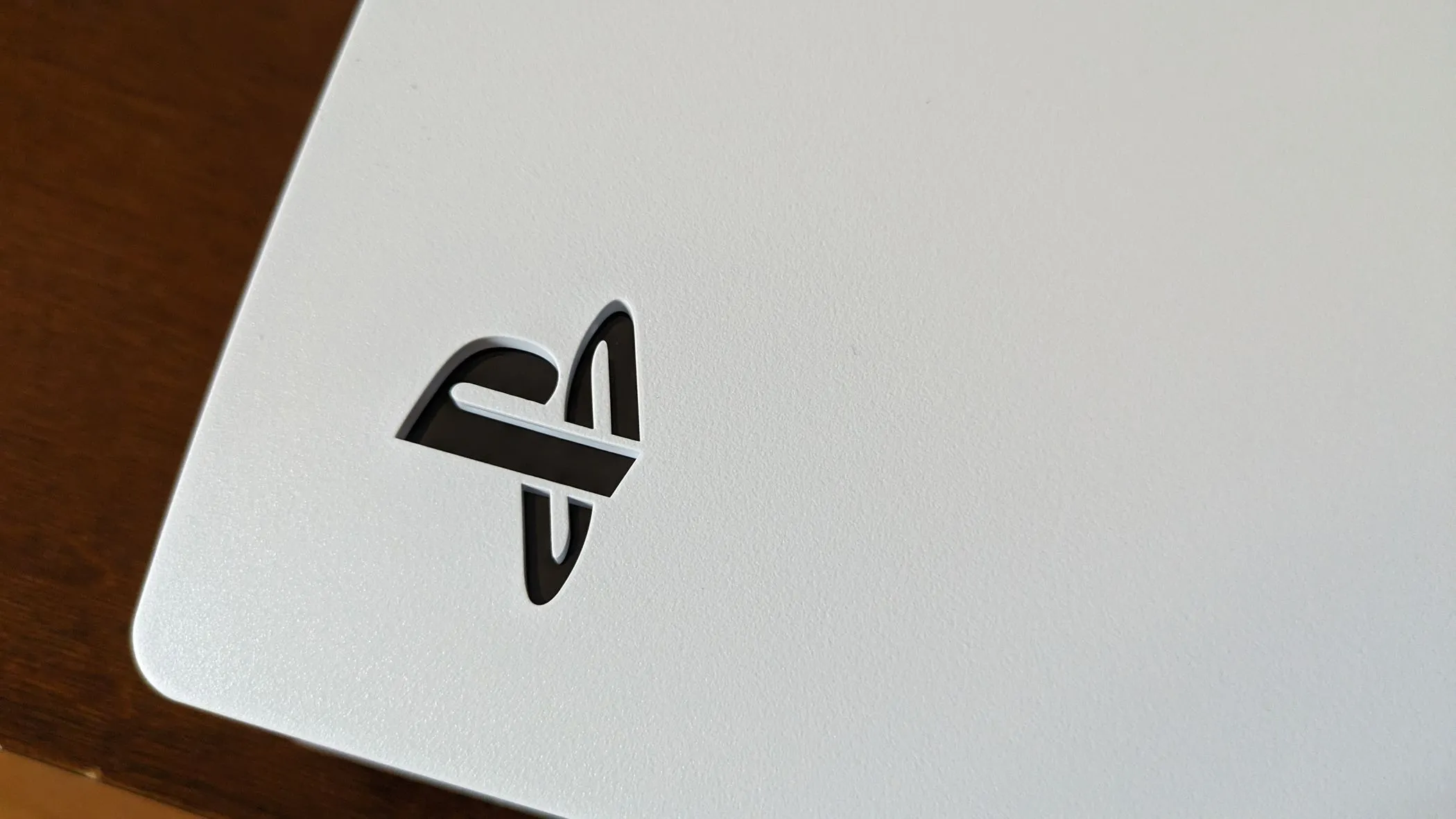 Logo PS5 màu trắng được chiếu sáng trên thân máy PlayStation 5 màu đen.