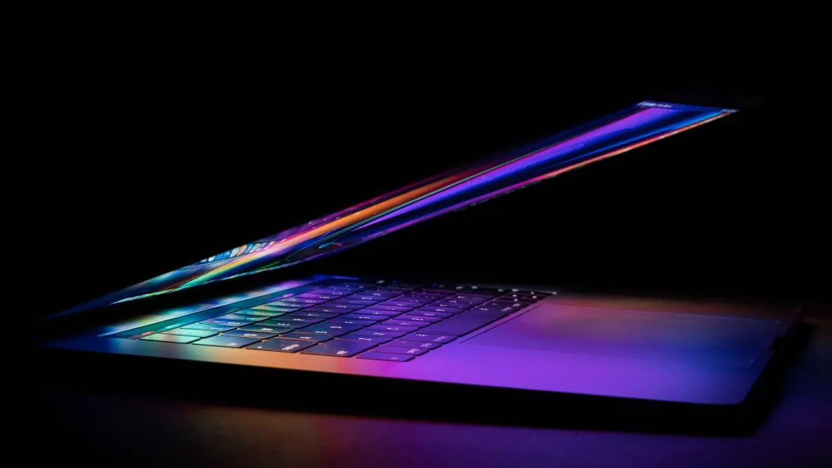 MacBook đang mở với màn hình hiển thị màu sắc rực rỡ, phản chiếu trên bàn phím