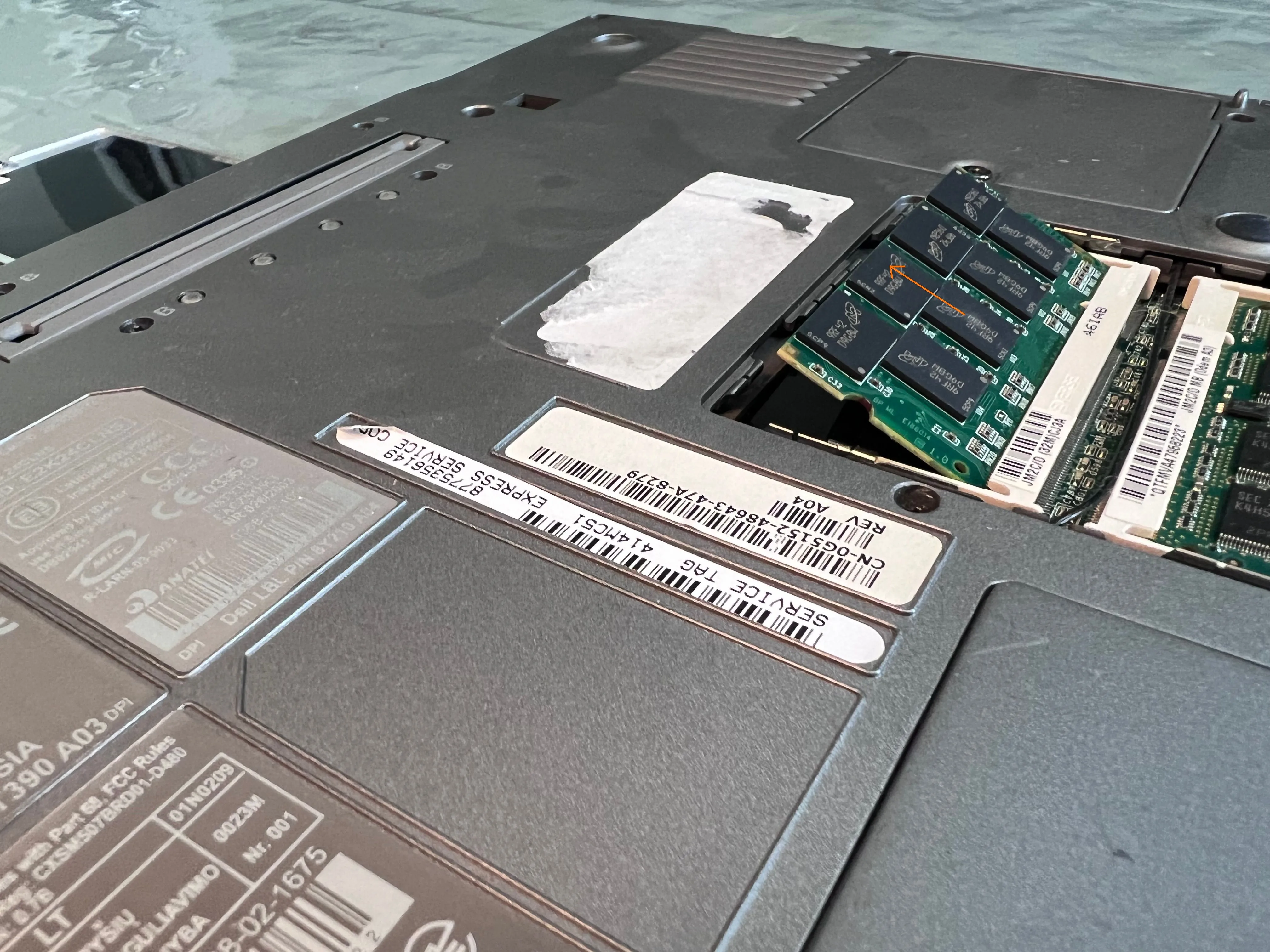 Mặt dưới của laptop Dell với thanh RAM đã được tháo một phần