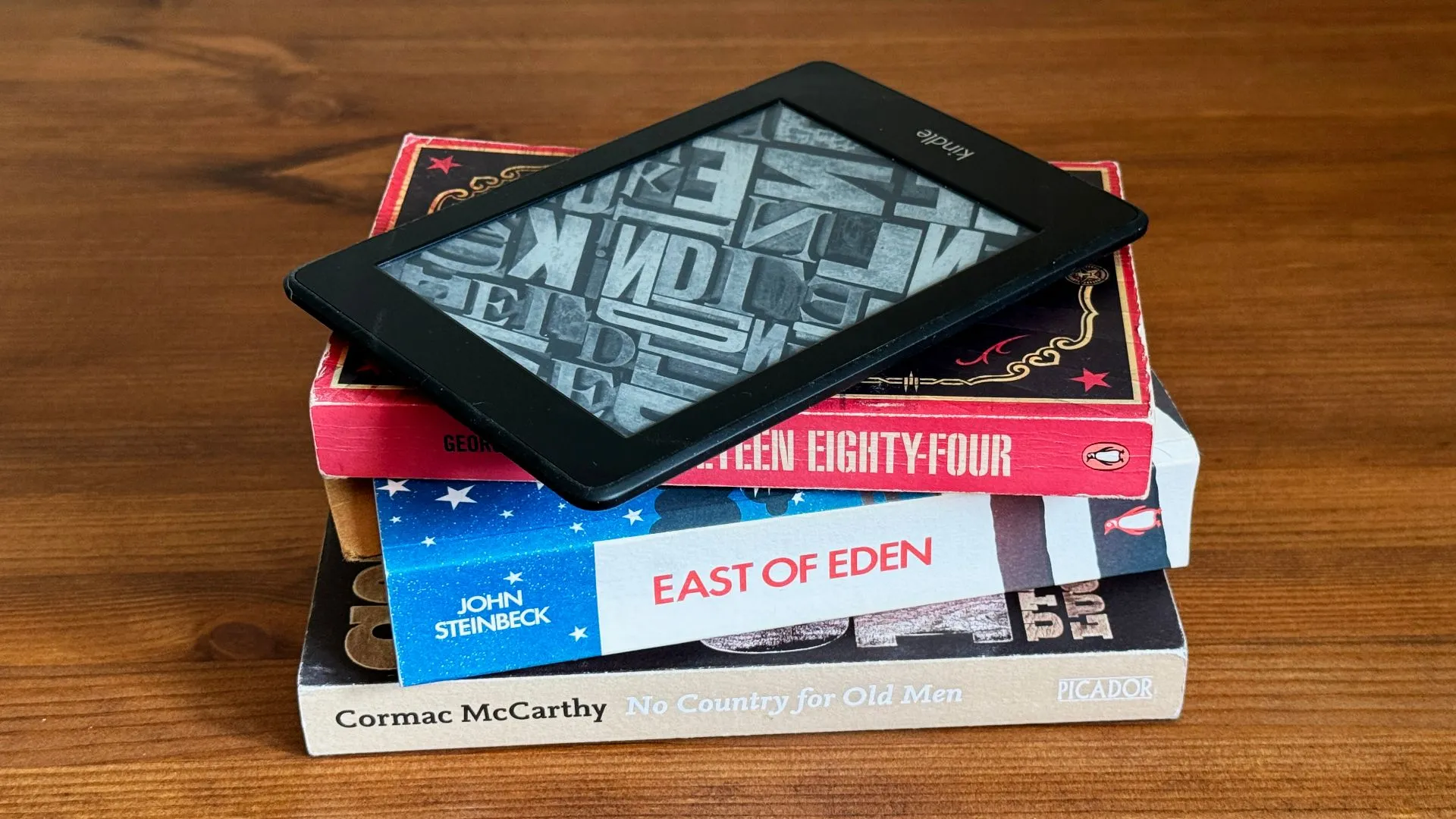 Máy đọc sách Kindle đặt trên chồng sách vật lý, biểu tượng của thư viện số và truyền thống