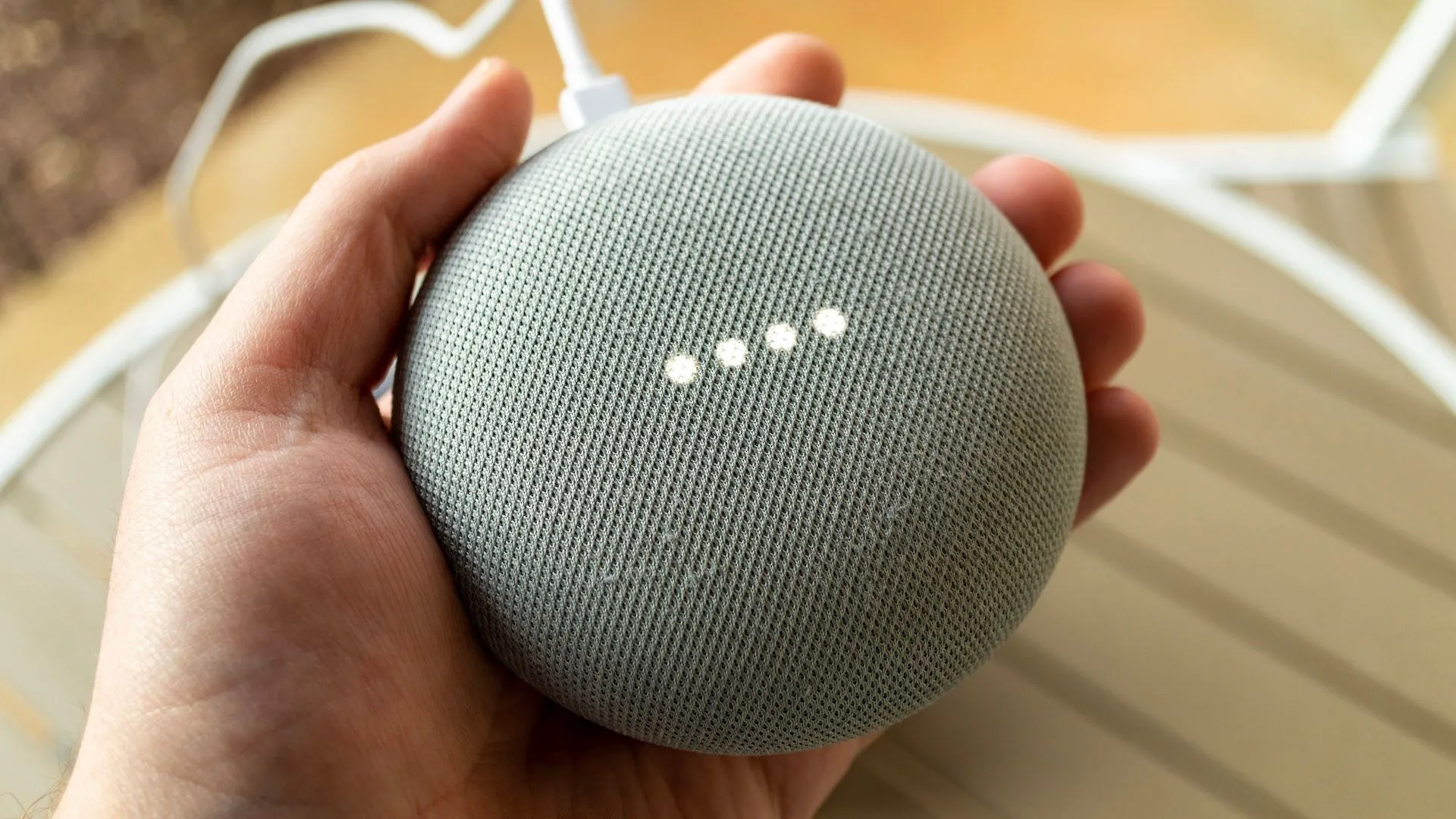 Một bàn tay đang cầm loa thông minh Google Nest, biểu trưng cho khả năng điều khiển qua trợ lý ảo
