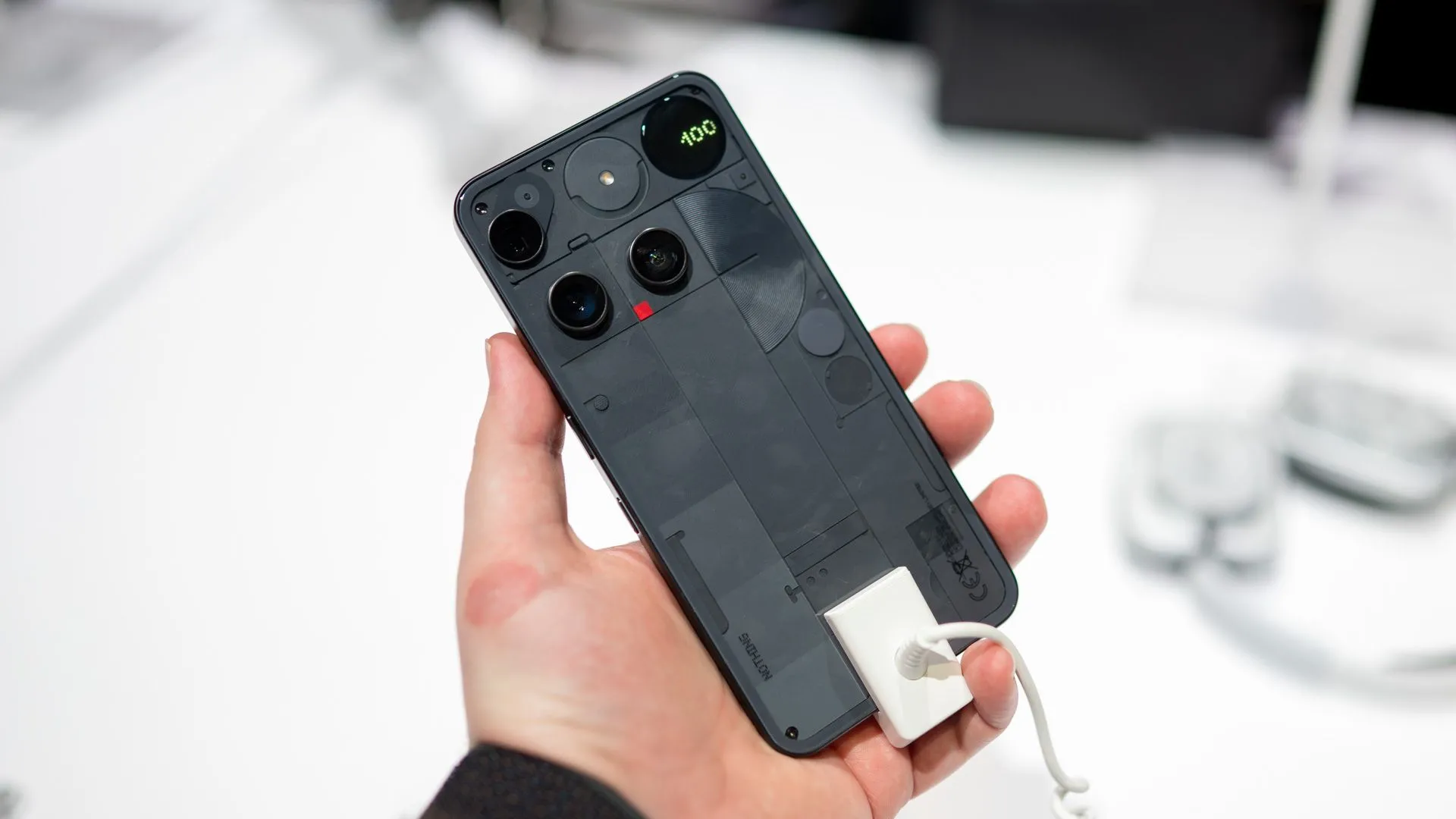 Một người đang cầm chiếc Nothing Phone 3, mặt lưng trong suốt với các thành phần bên trong và cụm camera được sắp xếp độc đáo.