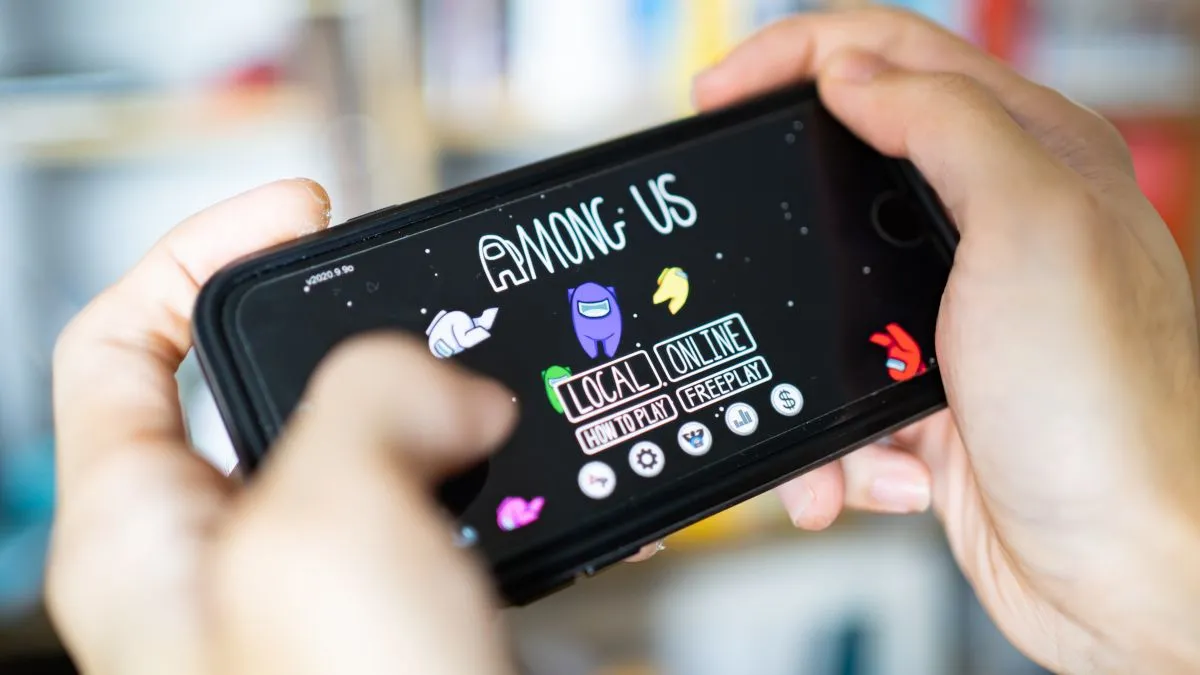Người chơi đang sử dụng điện thoại thông minh để trải nghiệm game Among Us, minh họa tính năng chơi co-op không dây.