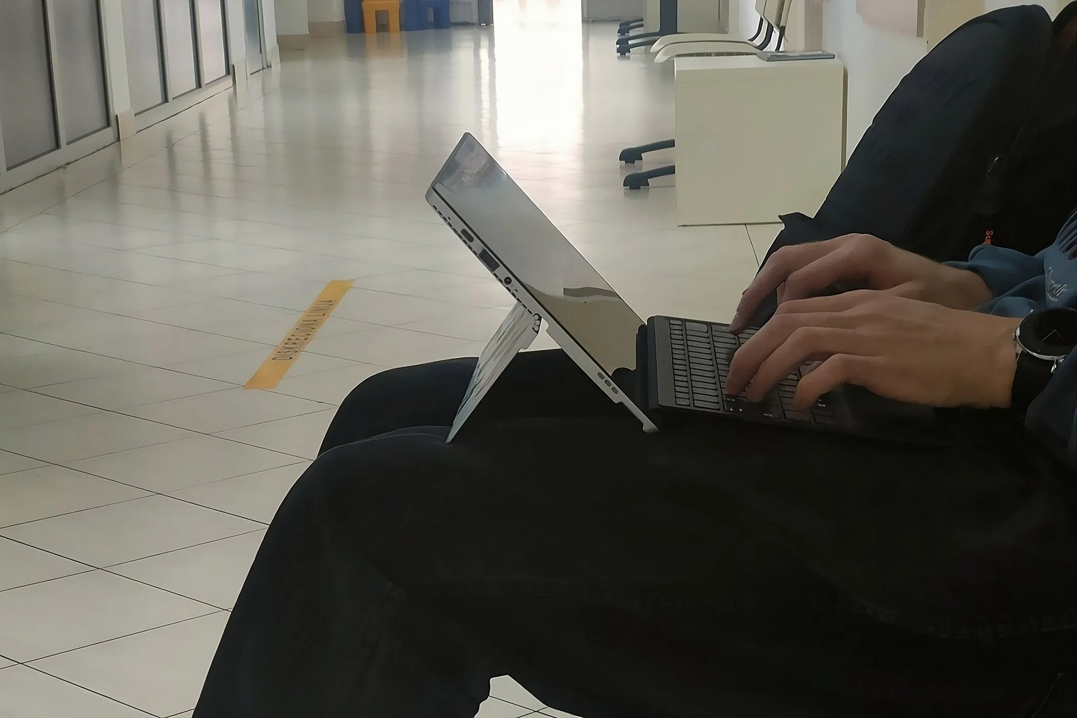 Người đang gõ trên laptop 2 trong 1 đặt trên đùi