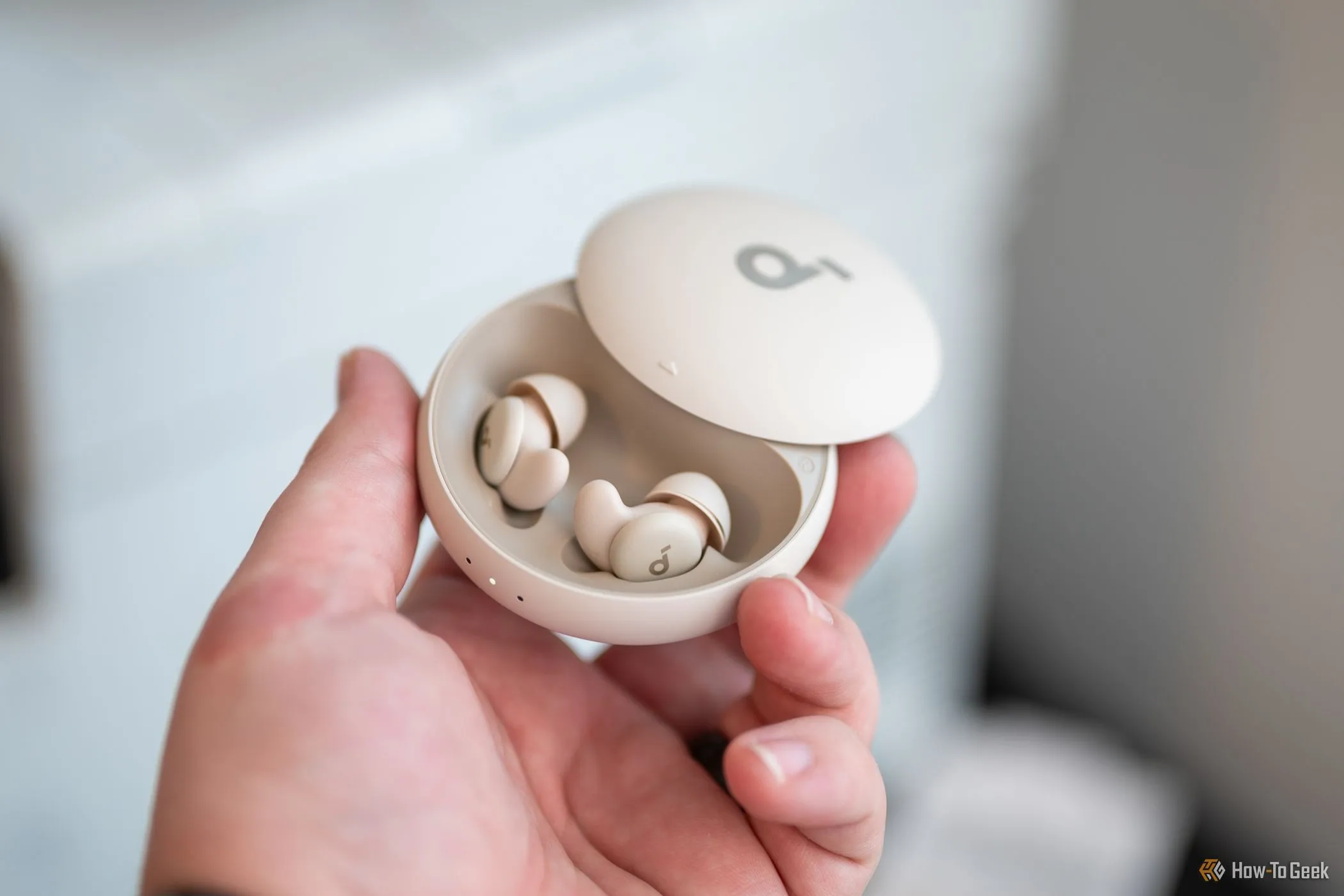 Người dùng cầm tai nghe Soundcore Sleep A20 bên trong hộp sạc, minh họa cho việc tai nghe luôn được sạc khi đặt trong hộp.
