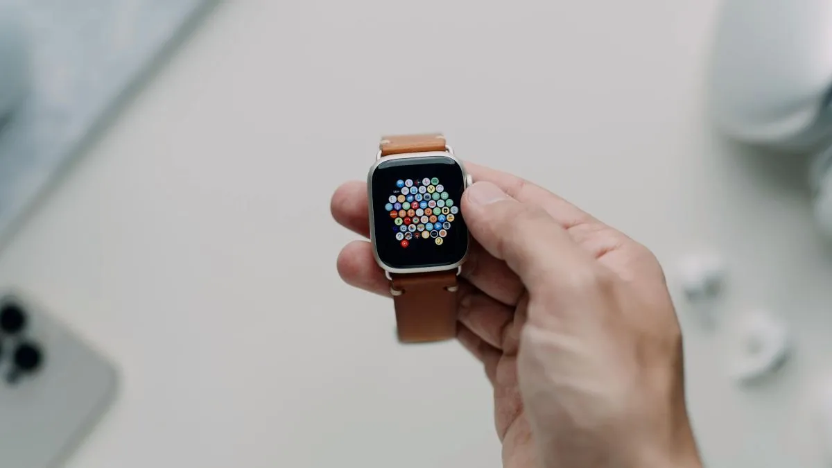 Người dùng đang cầm Apple Watch Series 7 với dây đeo da trên cổ tay.