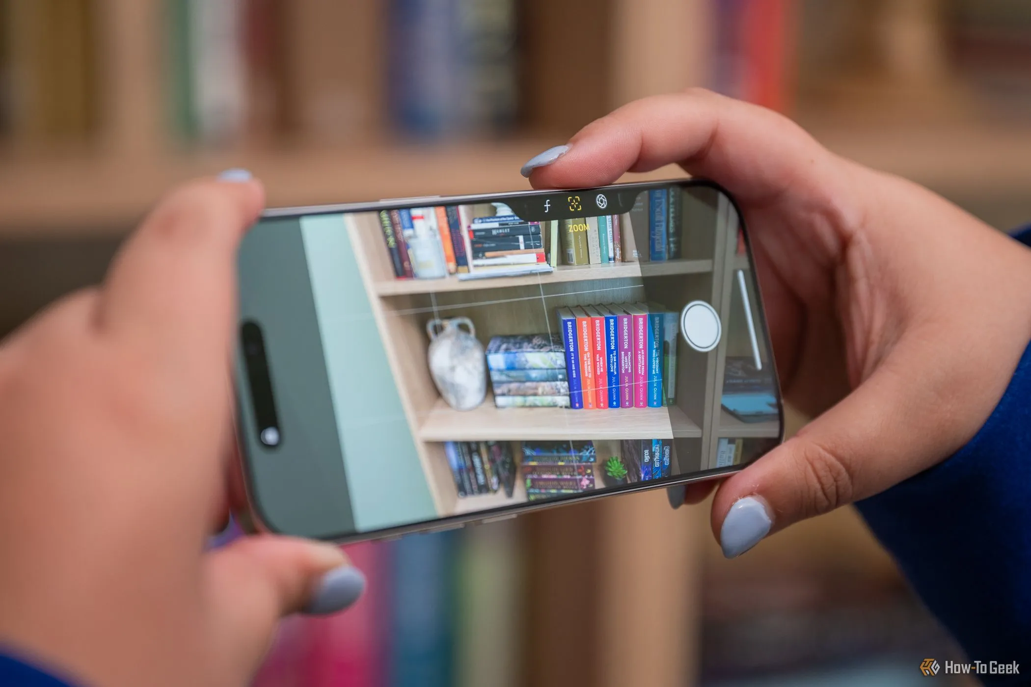 Người dùng đang thao tác với iPhone 16 Pro ở chế độ ngang, ngón tay cái trượt trên nút Camera Control để điều chỉnh các thiết lập camera như zoom, nâng cao trải nghiệm nhiếp ảnh.