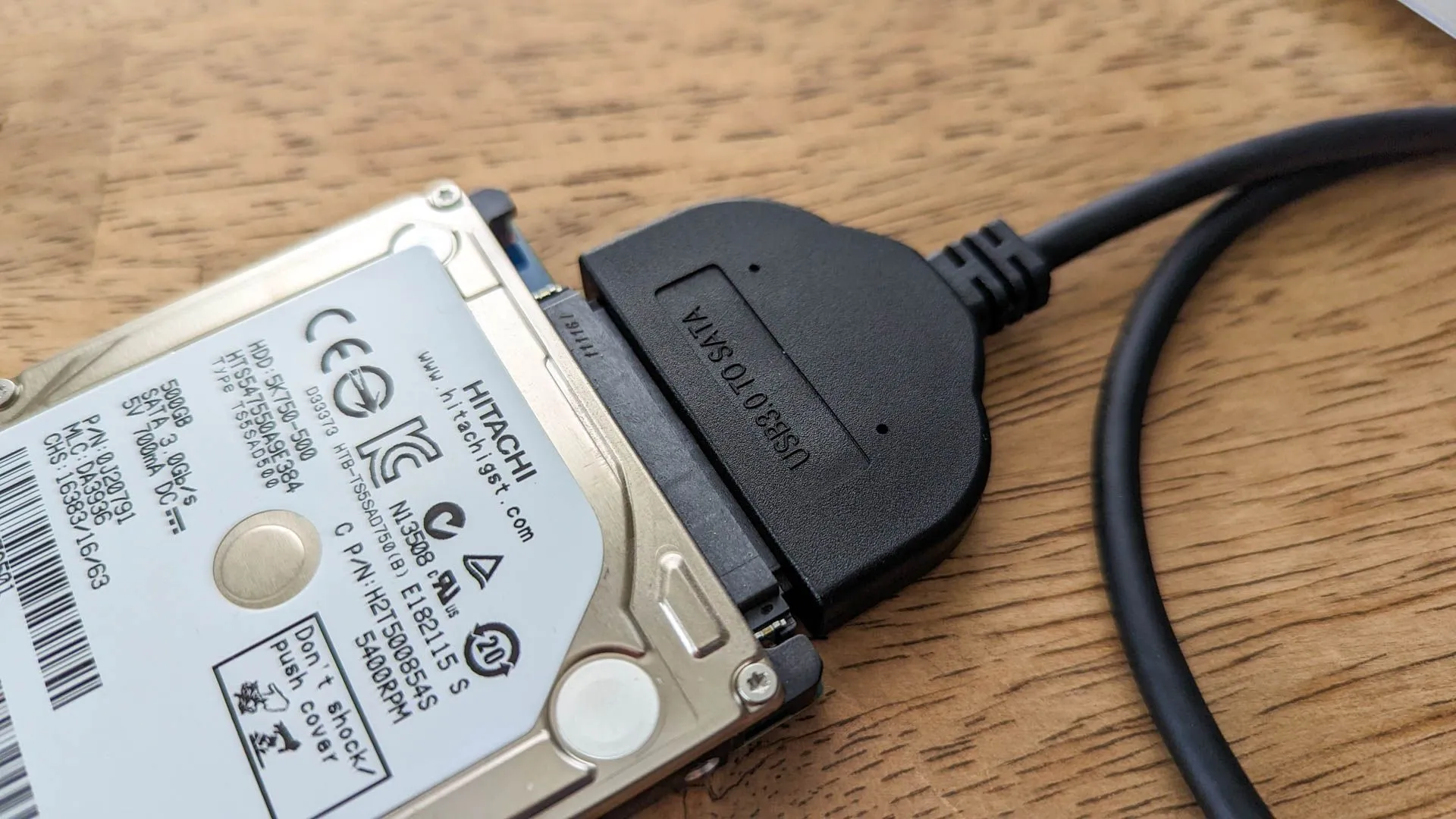 Ổ cứng HDD được kết nối với bộ chuyển đổi USB trên bề mặt gỗ