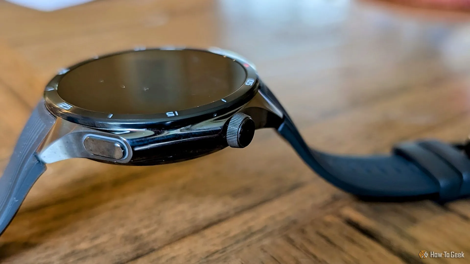 OnePlus Watch 3 đặt trên mặt bàn, phô bày nút xoay vật lý mới.