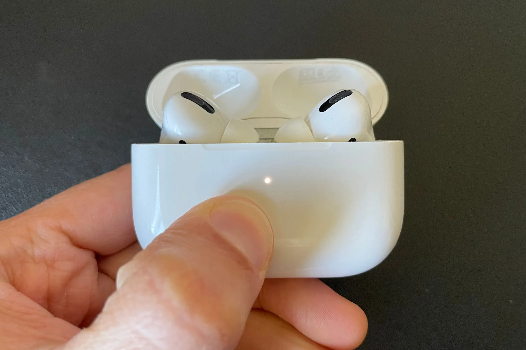 Tai nghe AirPods Pro bên trong hộp sạc với đèn trạng thái màu trắng.