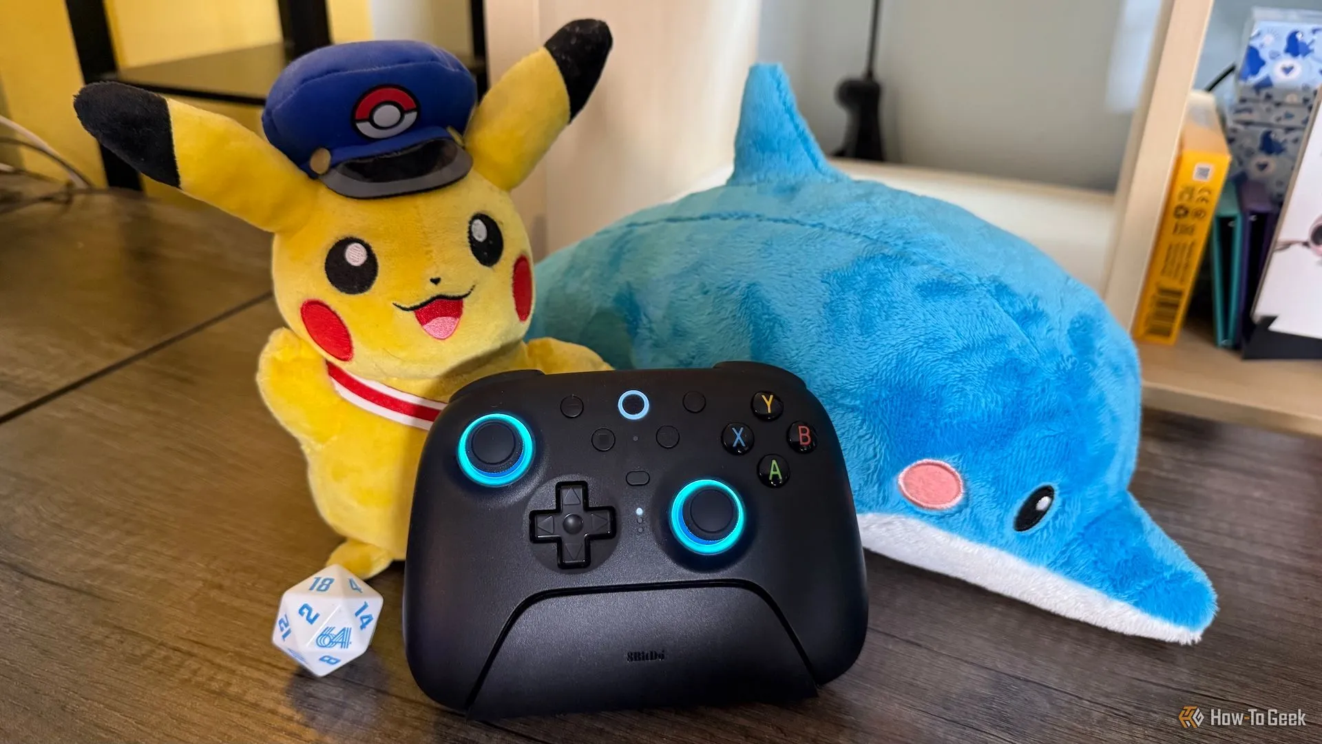 Tay cầm 8BitDo Ultimate 2 Wireless trên dock sạc, cùng các vật phẩm gaming tạo không khí chơi game sống động.
