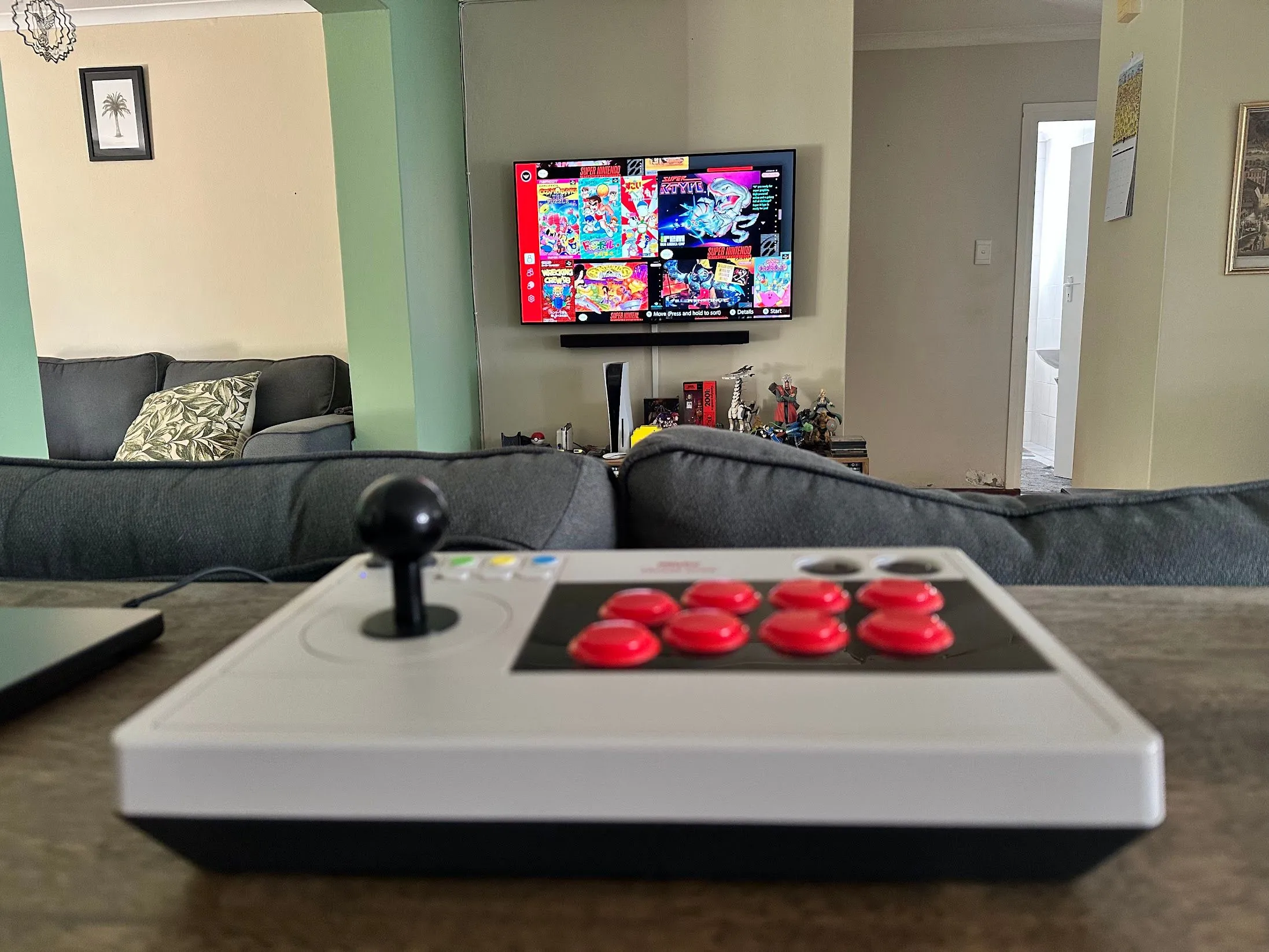 Thiết bị điều khiển arcade fight stick của 8bitDo, hiển thị trên màn hình là các tựa game SNES cổ điển, minh họa khả năng tái hiện trải nghiệm game thùng và game retro.