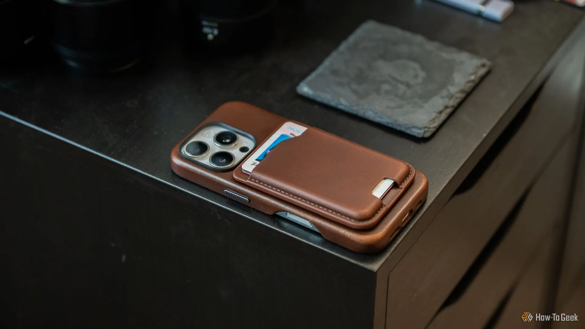 Ví da Nomad Mag Wallet gắn vào iPhone 16 Pro đặt trên bàn, minh họa tính năng Flip to Shhh giúp điện thoại im lặng khi úp màn hình