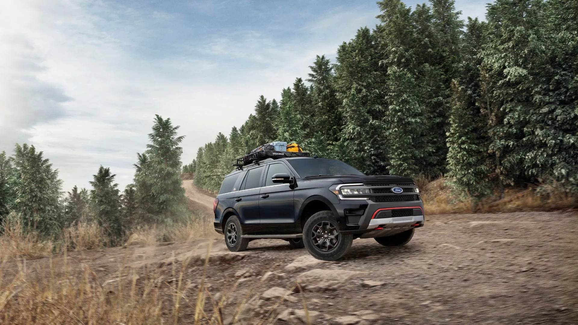 Xe Ford Expedition Timberline 2024 màu xanh đậm đỗ trên đường đất với khung cảnh rừng núi phía sau