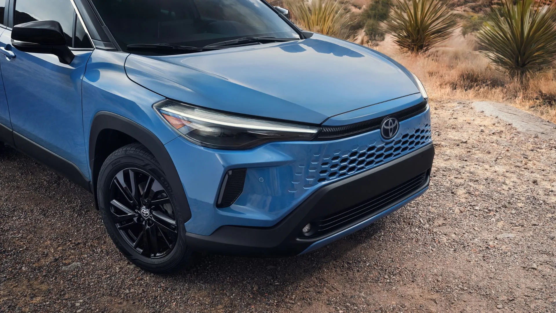 Xe Toyota Corolla Cross 2026 màu trắng, thiết kế hiện đại, đỗ trên đường với cây xanh phía sau