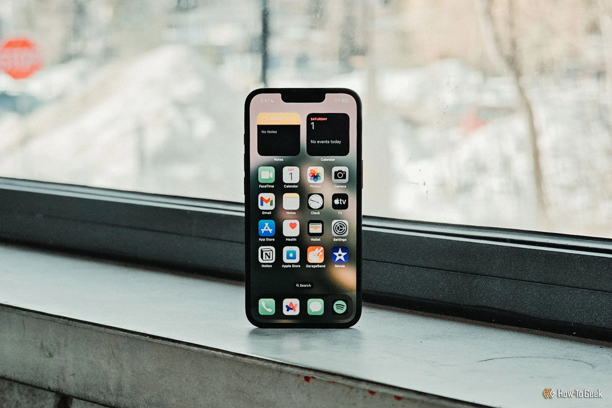 Màn hình chính iPhone 16e hiển thị các biểu tượng ứng dụng với độ sáng rõ nét, đặt phía trước cửa sổ, làm nổi bật chất lượng tấm nền Super Retina XDR