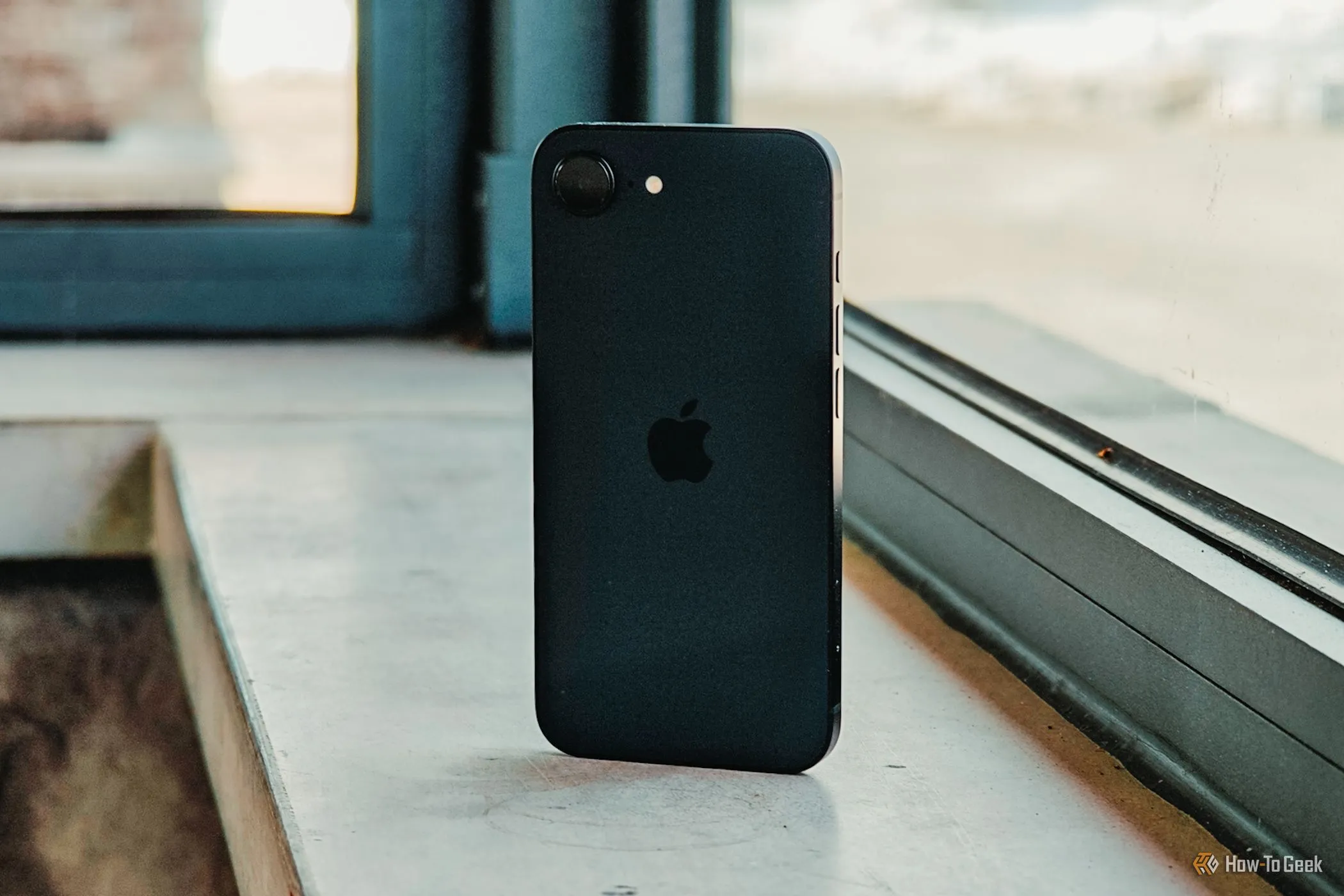 Mặt lưng iPhone 16e đặt nghiêng trước cửa sổ, làm nổi bật thiết kế thanh lịch và chip A18 mạnh mẽ mang lại hiệu năng ổn định cùng pin bền