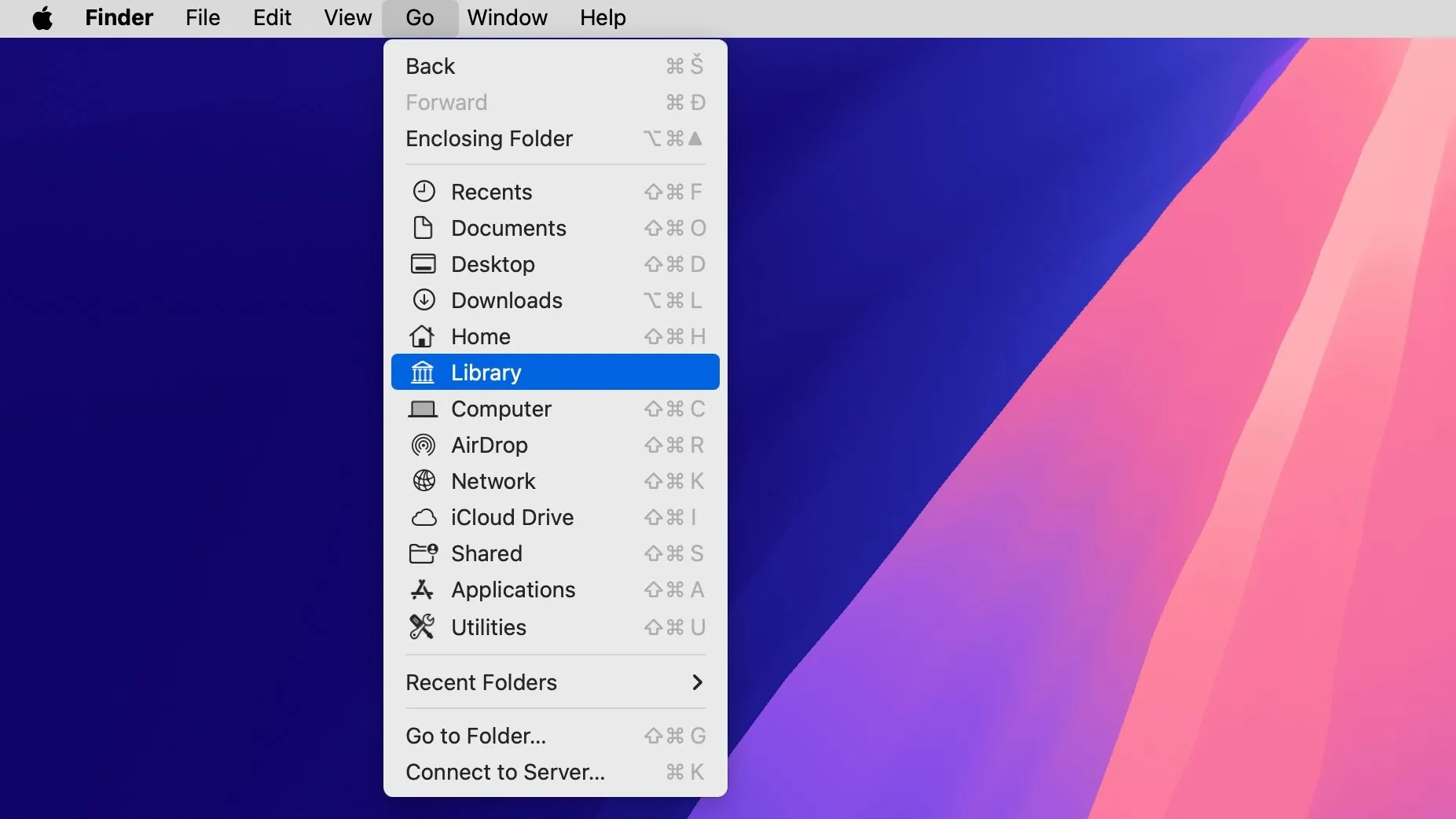 Màn hình nền macOS với Finder đang mở menu Go, tùy chọn &quot;Library&quot; được chọn.