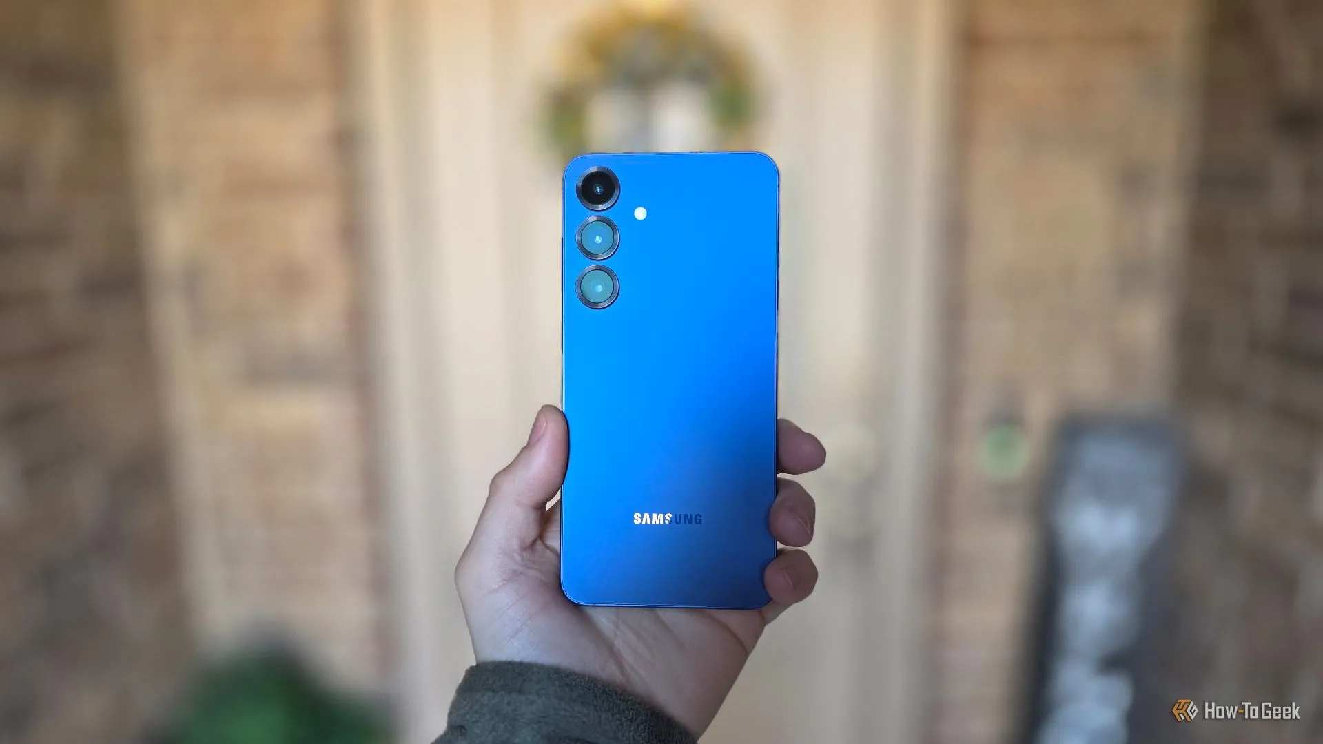 Mặt lưng của Galaxy S25 Plus màu xanh, đặt trên nền hiên nhà.