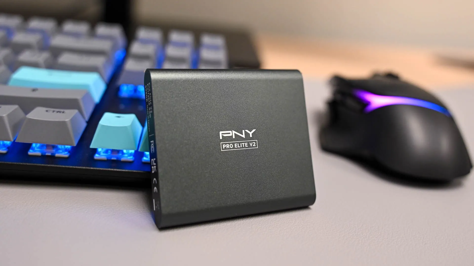 Ổ cứng di động PNY Pro Elite V2 đặt cạnh bàn phím, biểu tượng cho tốc độ và hiệu suất lưu trữ.